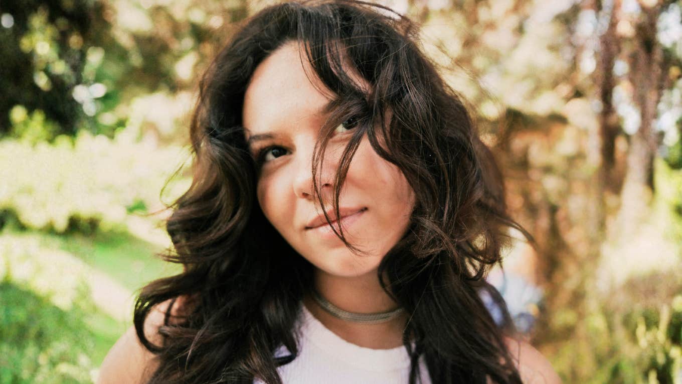 How To Know If You Love Him, Or If You're Just Attached  Woman with long hair in a park, pondering if she truly loves him or is just emotionally attached