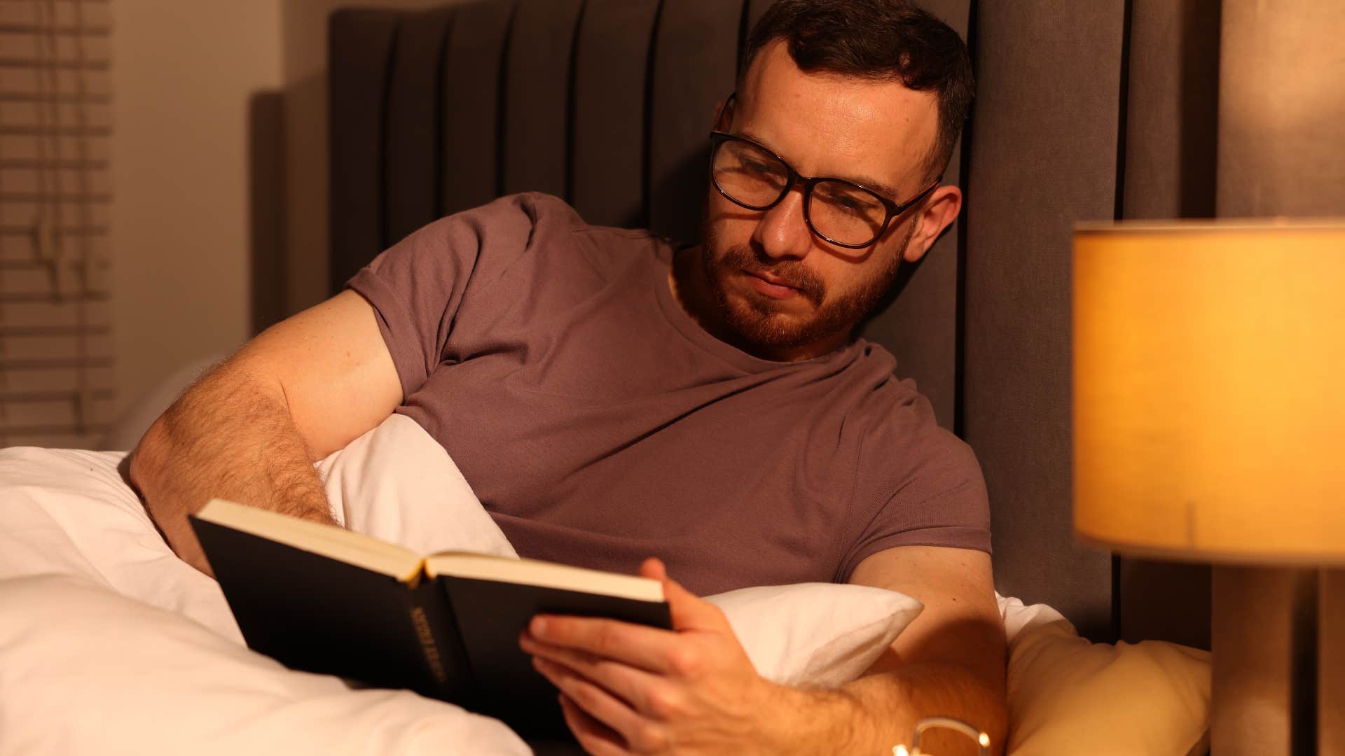 man who feels more relaxed on his own reading in bed
