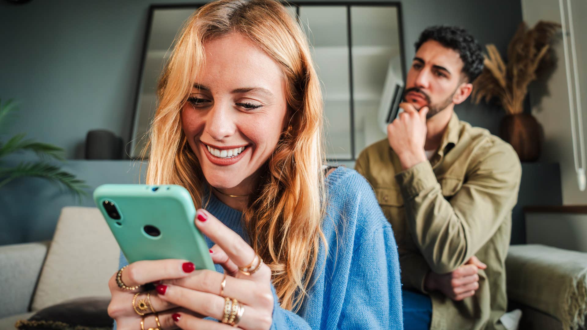 woman flirting on text while husband looks upset