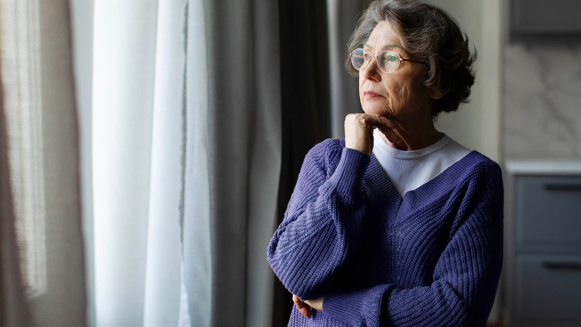 Woman who's stopped sharing her inner world looking out a window.