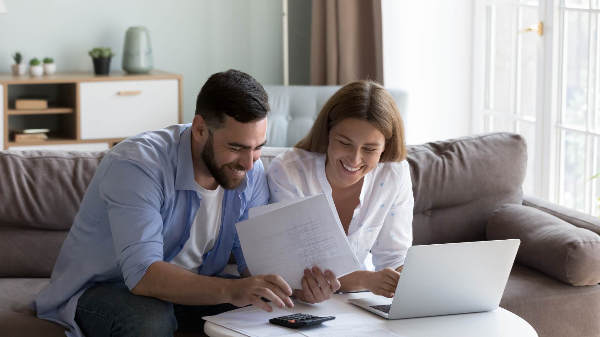 couple calculating bills in front of laptop