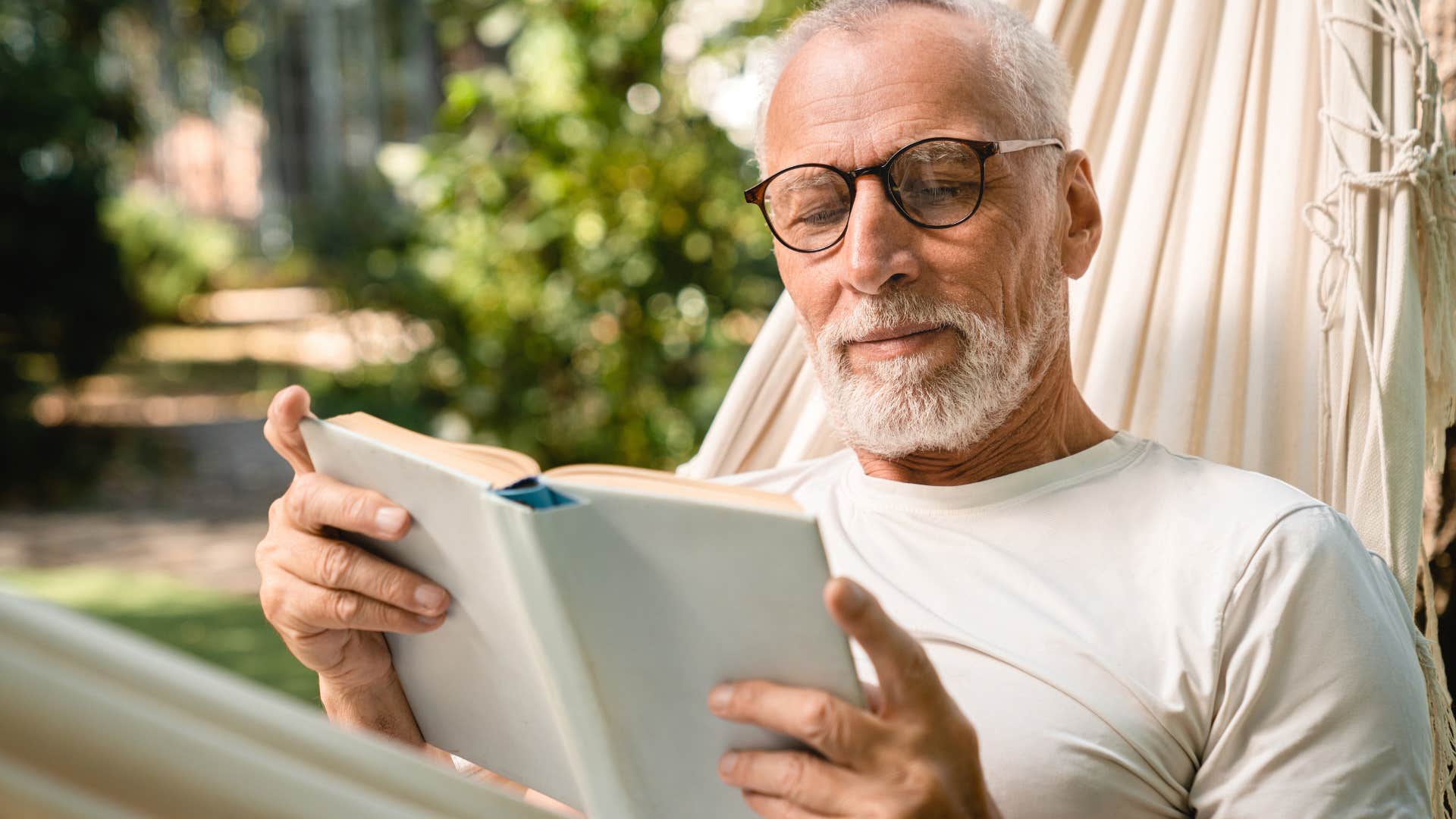 older man reading book outside