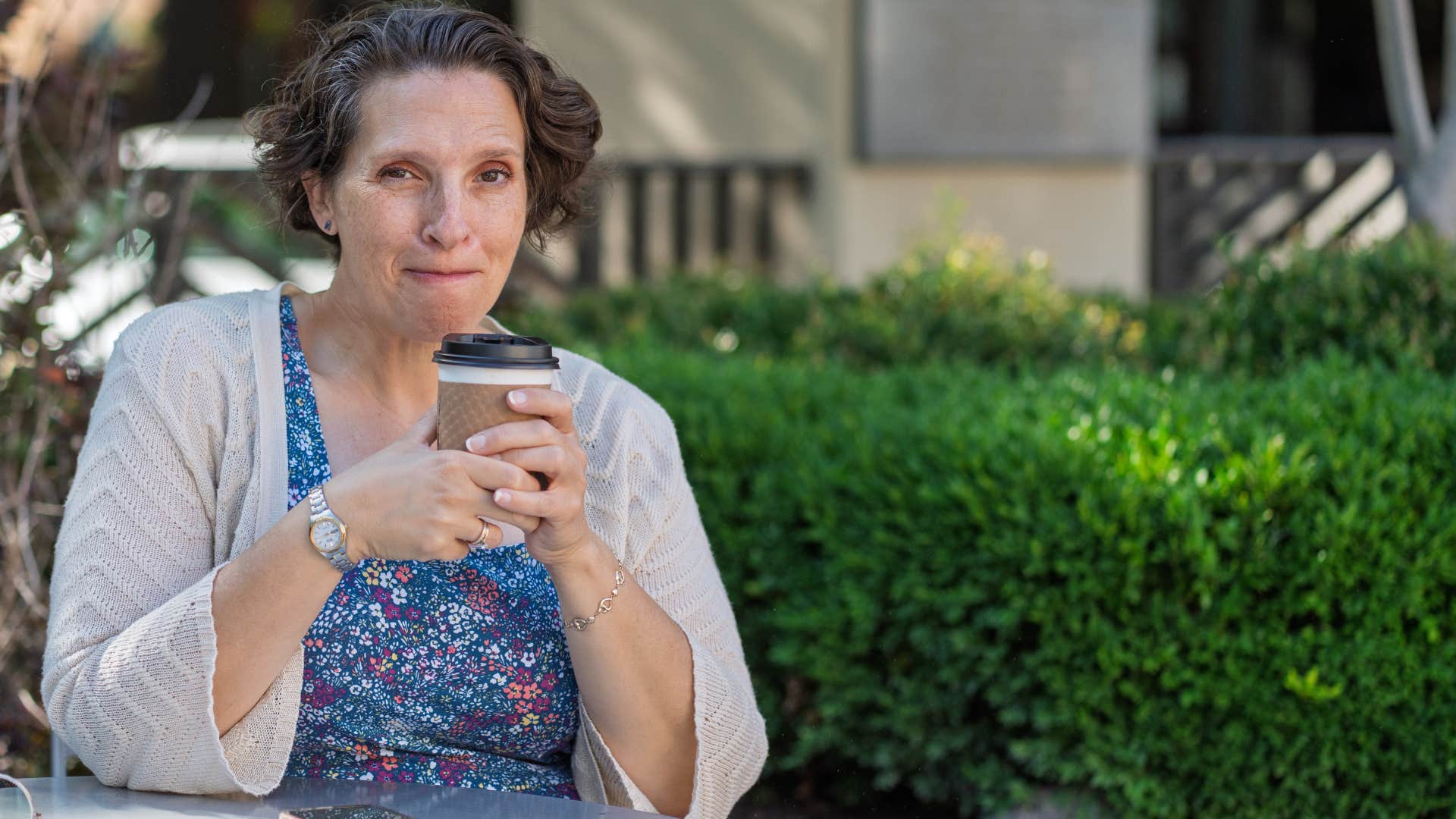 older woman smiling while drinking coffee