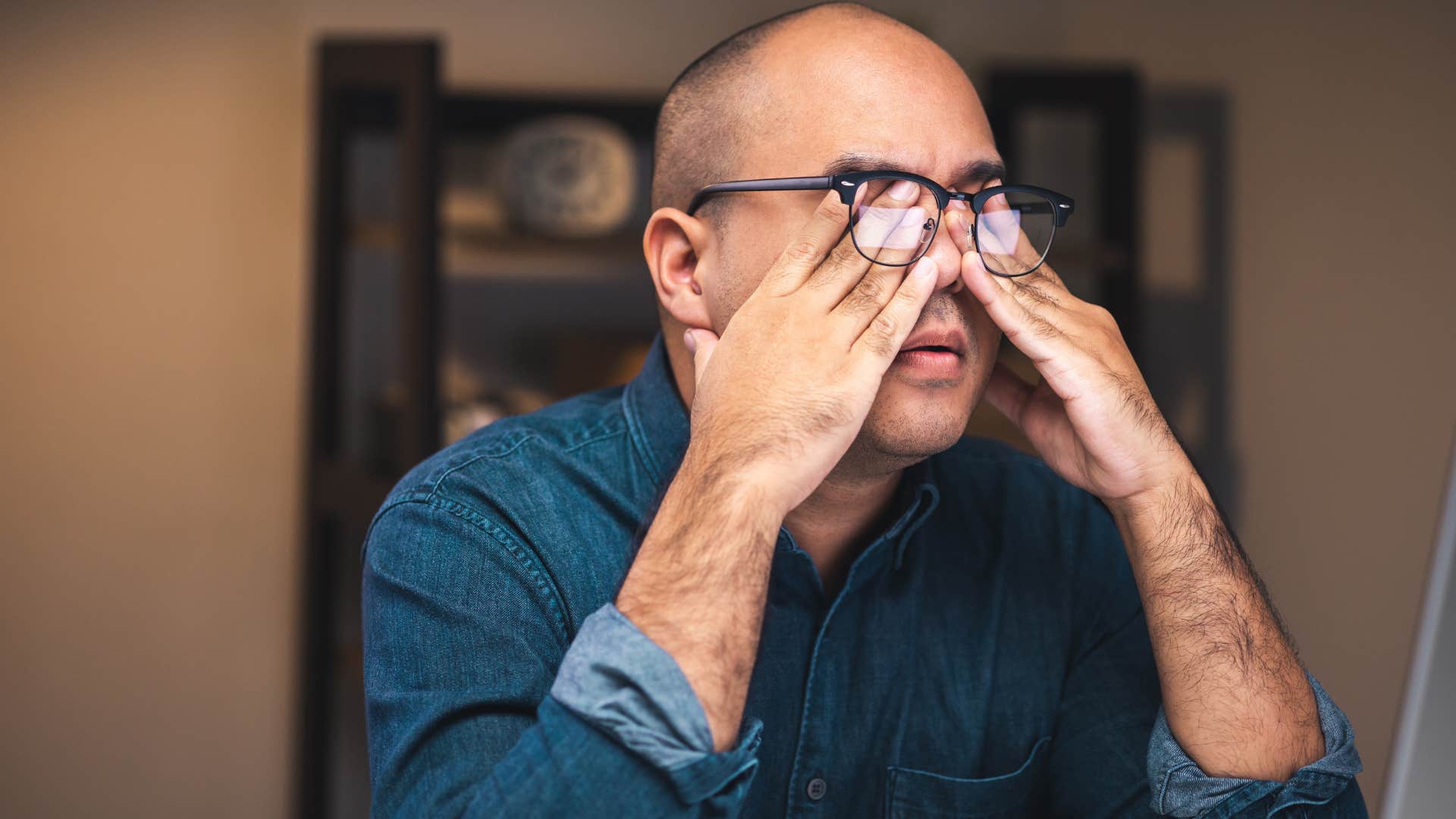Man rubbing his eyes when the lights are always on.