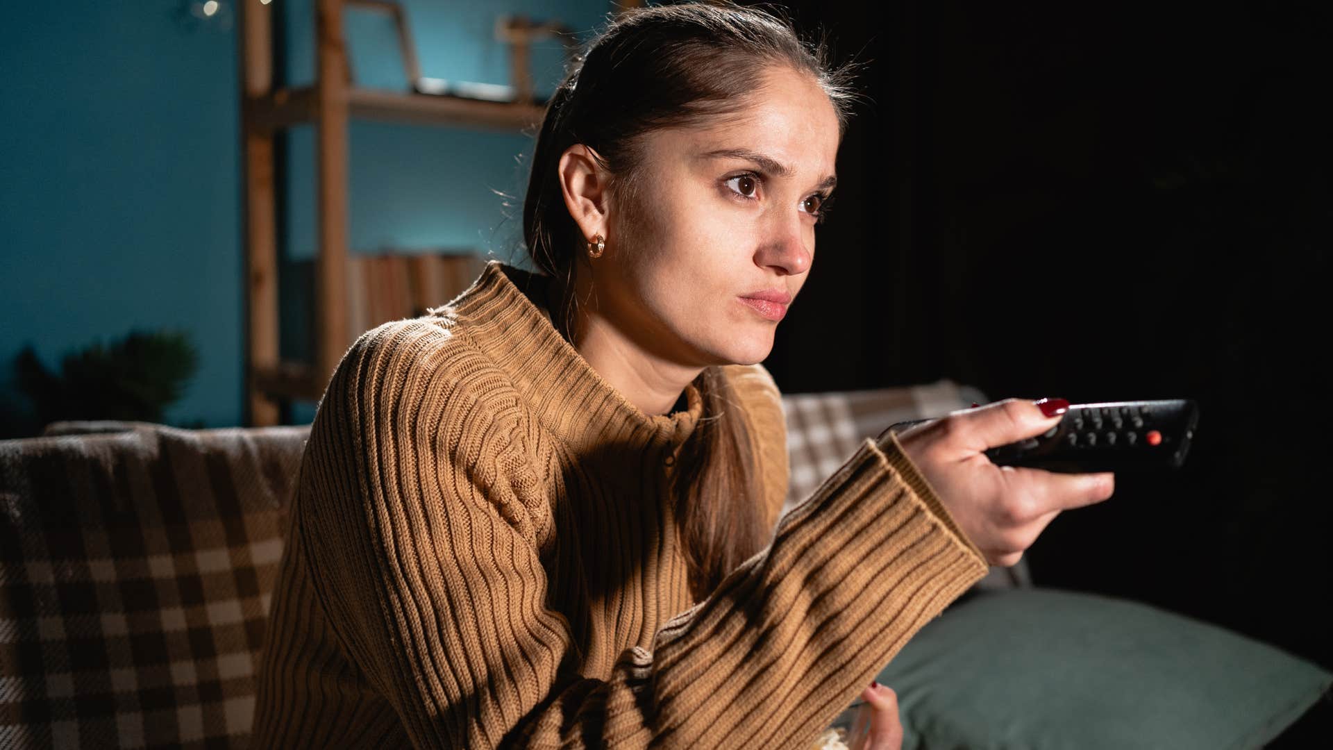 Woman at home with a TV always playing in the background.