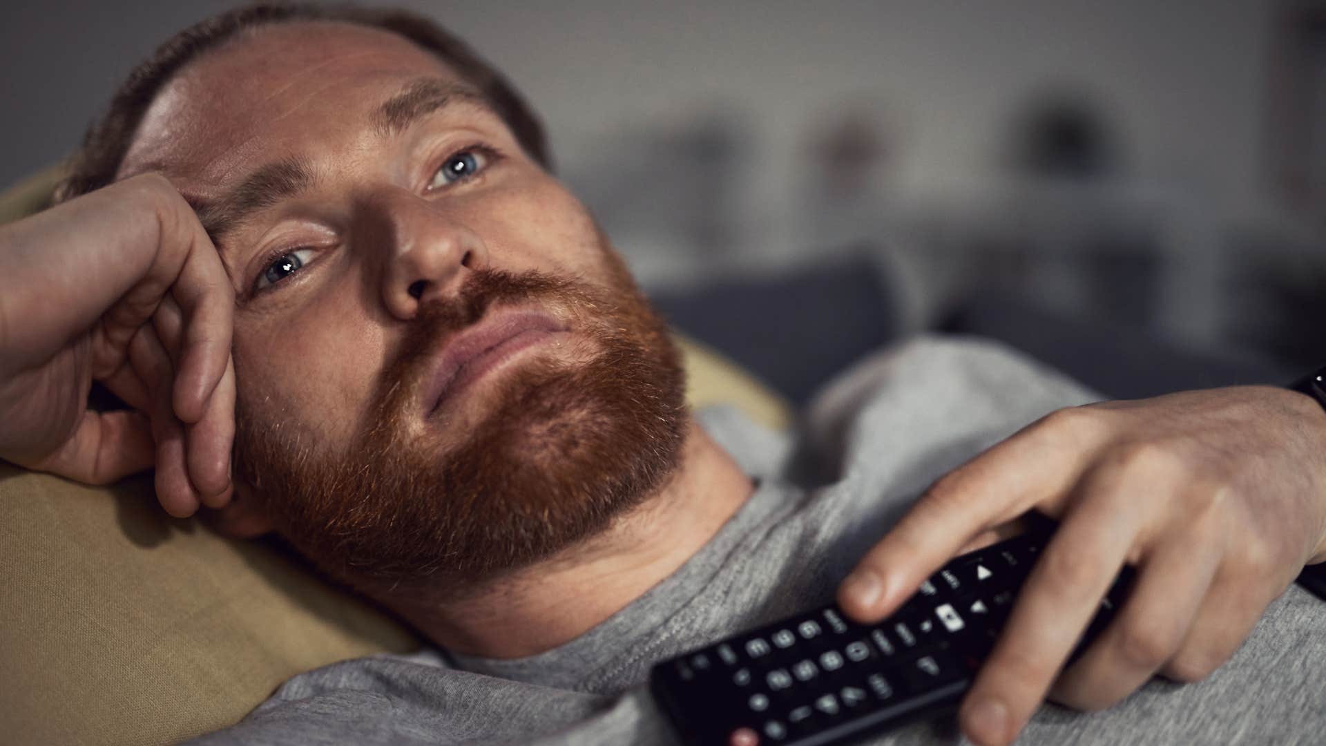 man binge-watching comfort show sitting on the couch