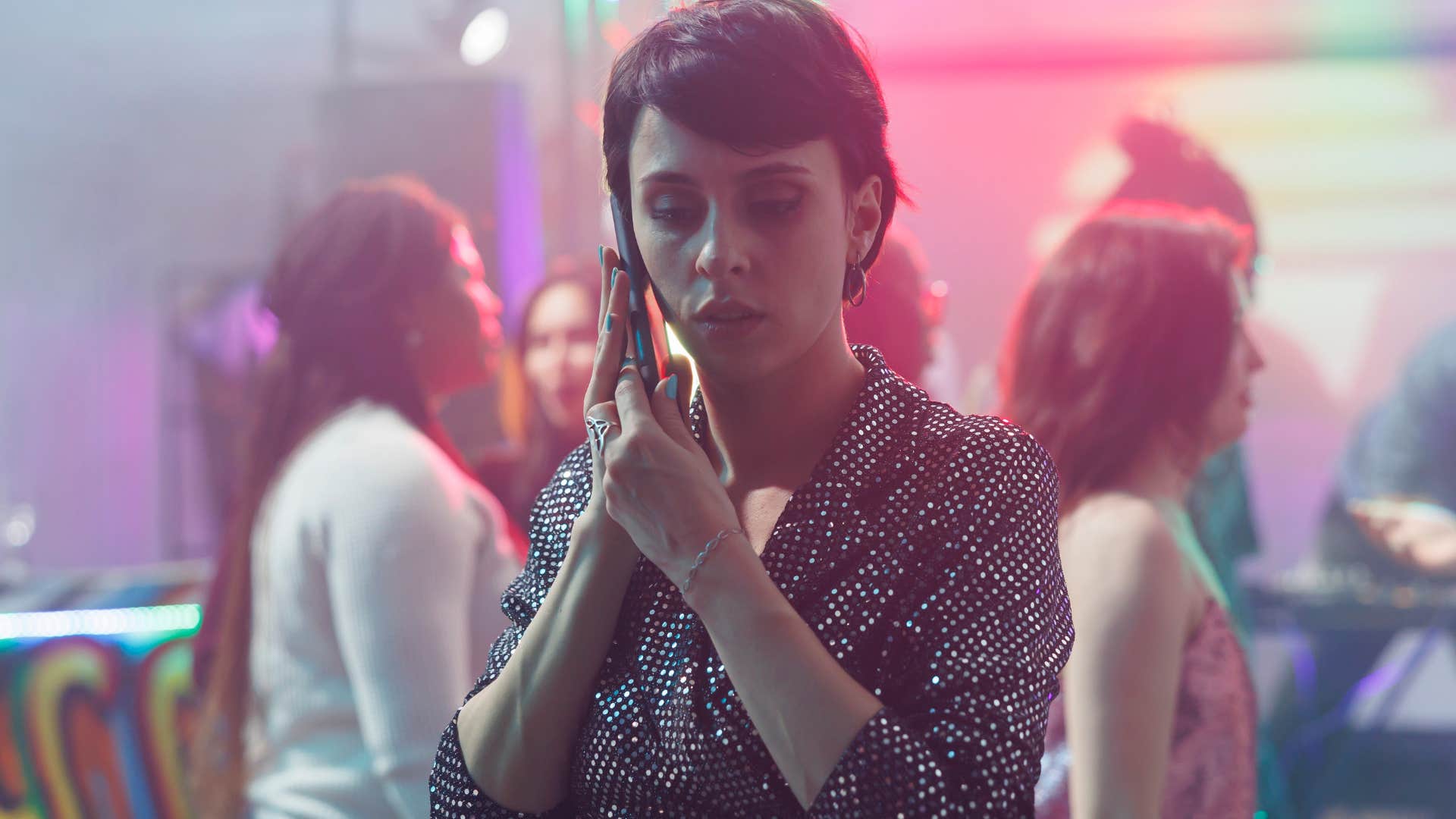 introverted woman looking nervous talking on the phone at overcrowded party