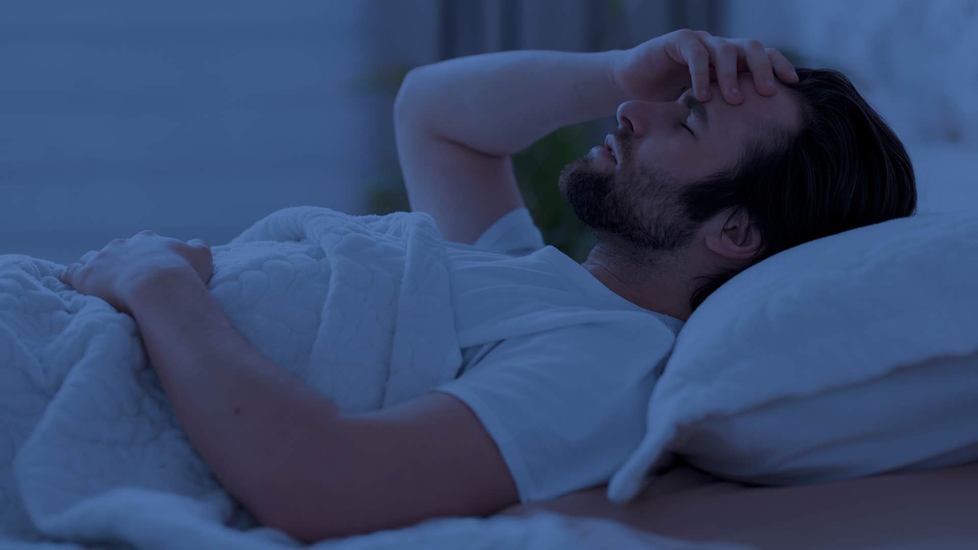 Hypervigilant man lying awake in bed.