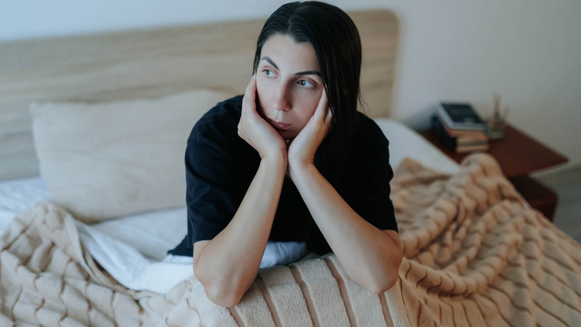 Woman who's secretly superstitious sitting in her bed.