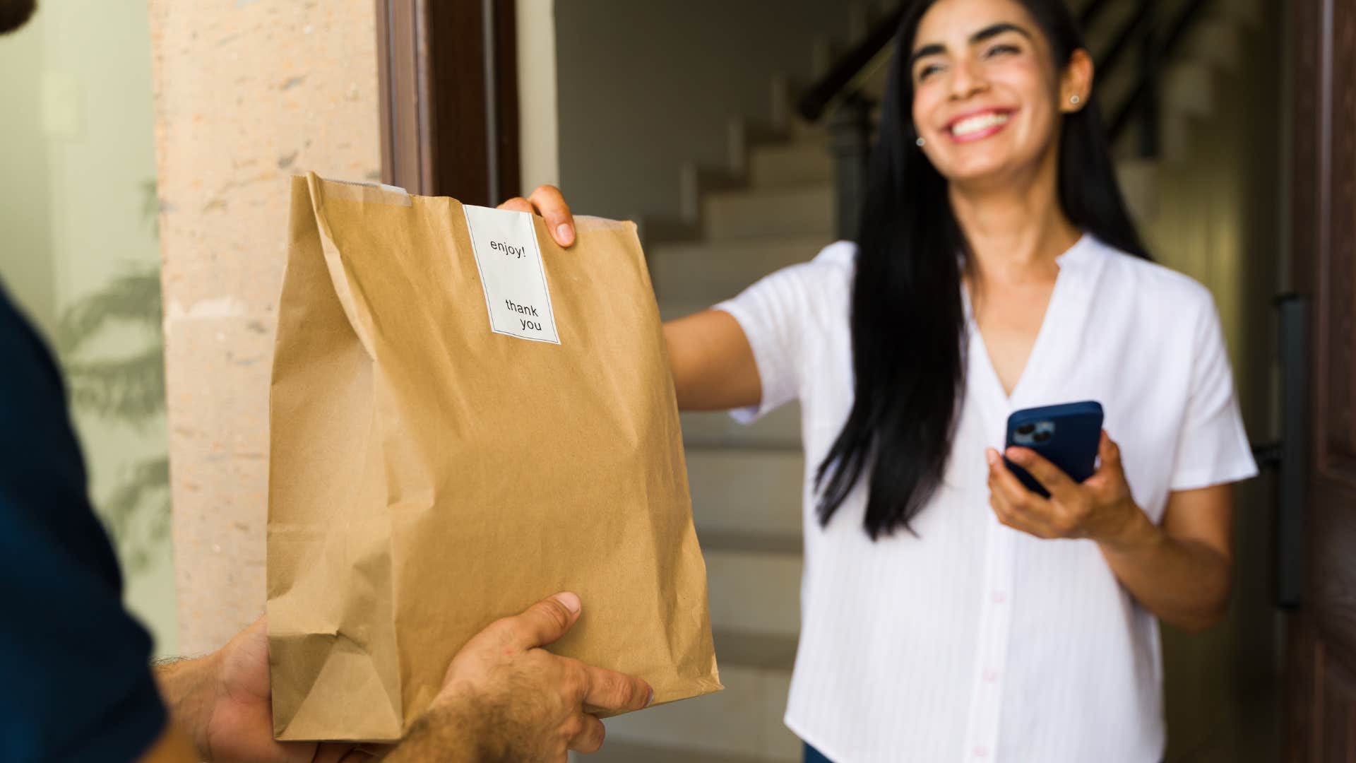woman paying delivery fee grabbing food from driver