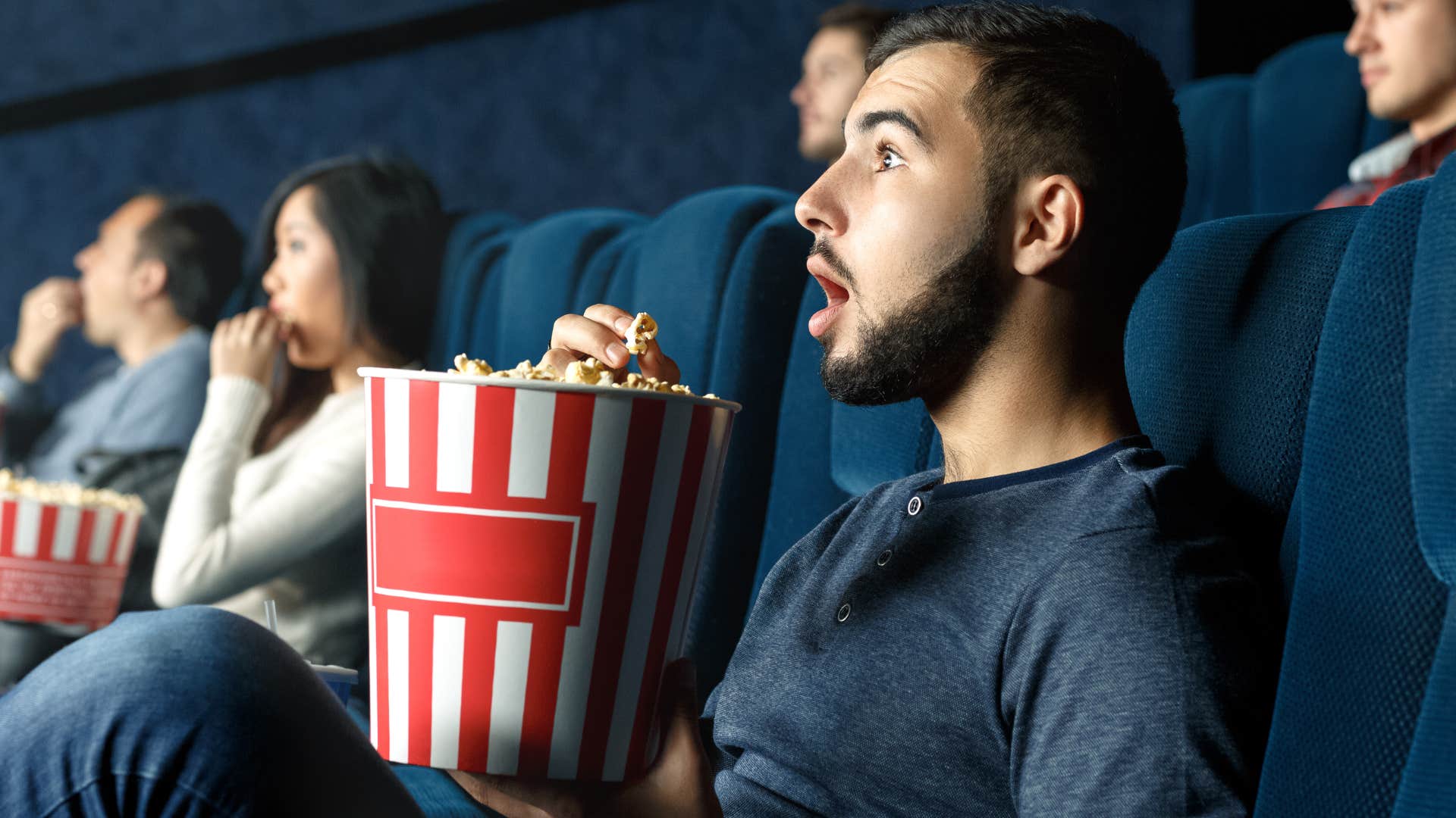 man eating movie theater popcorn watching the screen