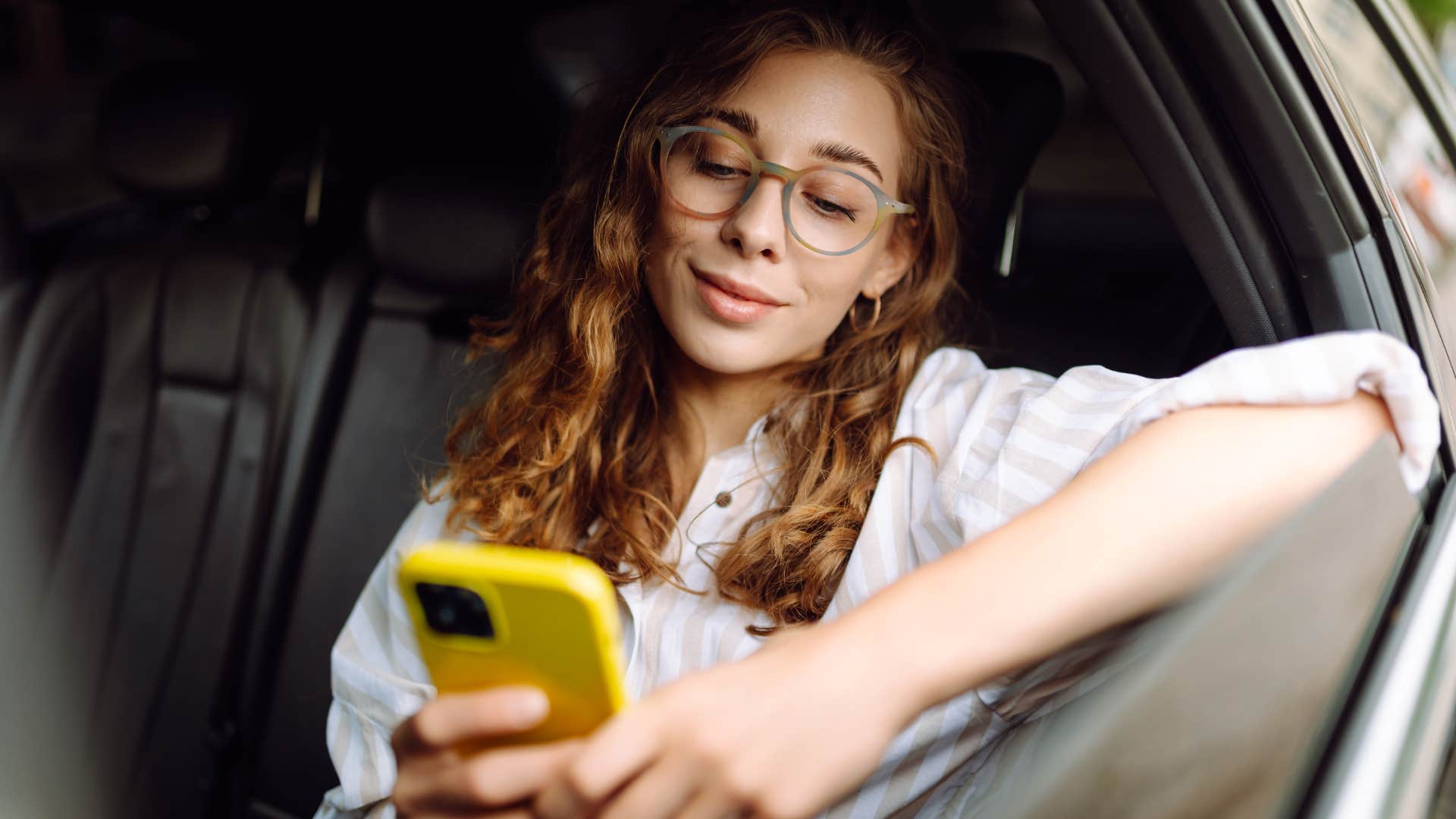 woman smiling and texting in a ride-share