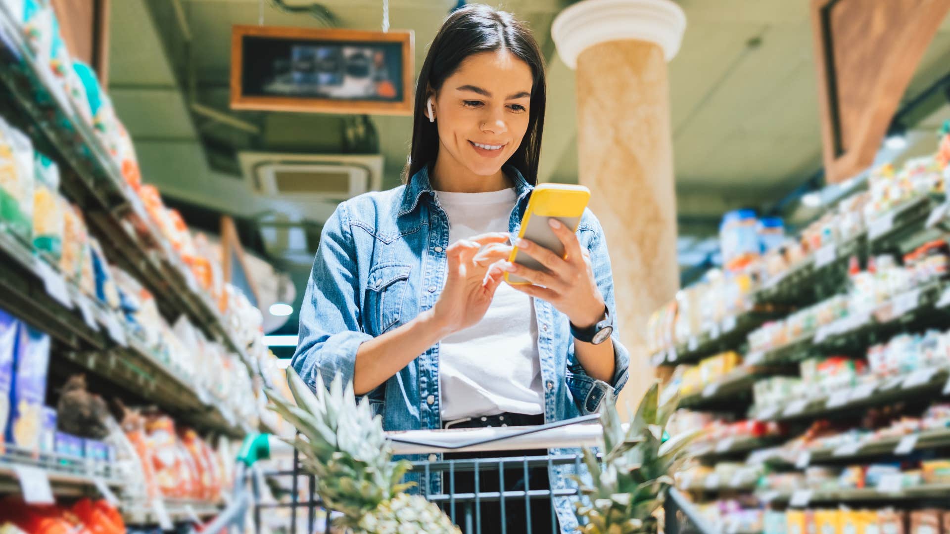 Woman using loyalty programs and online coupons in the grocery store.