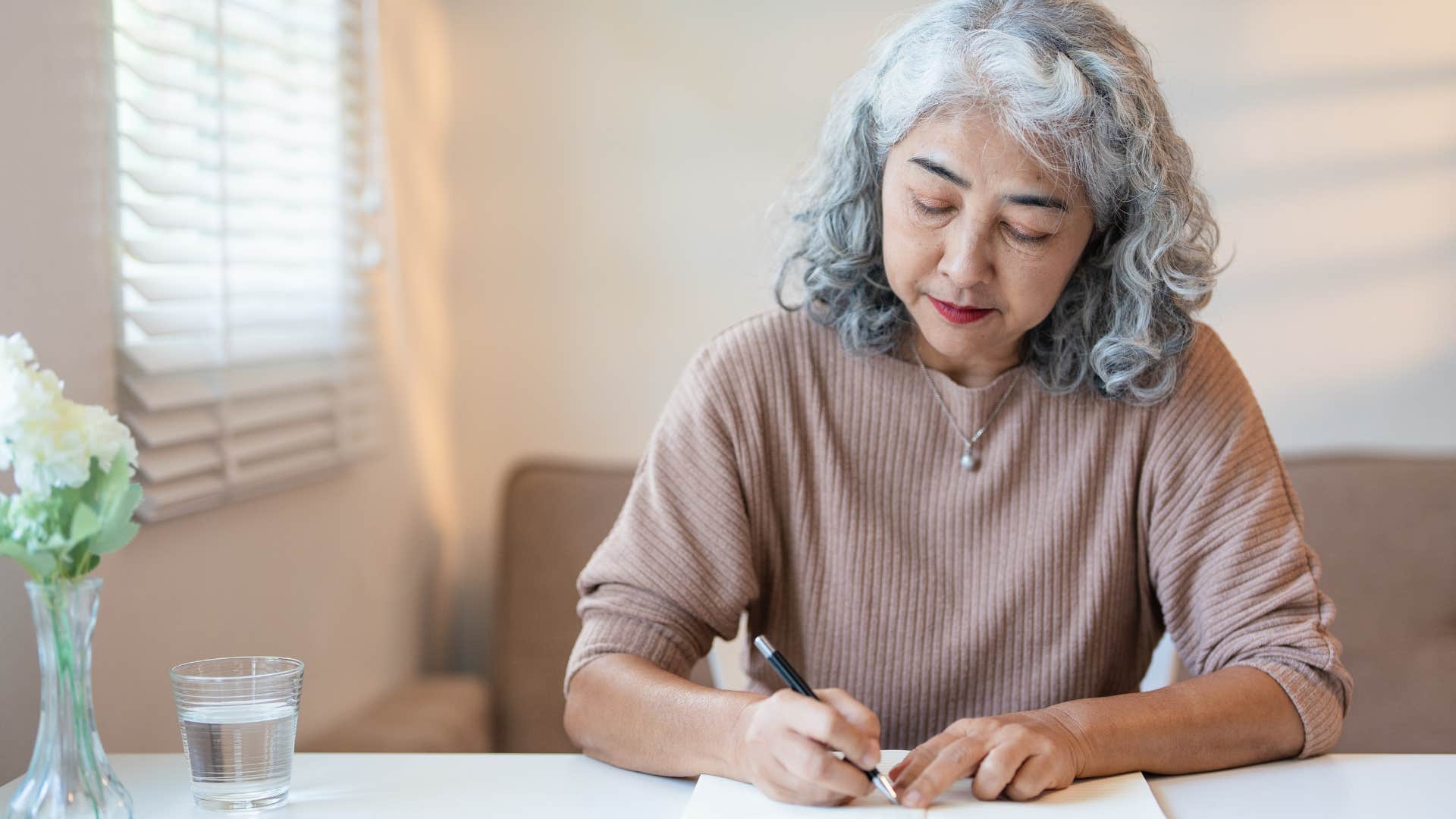 older woman with lots of hobbies writing at her desk