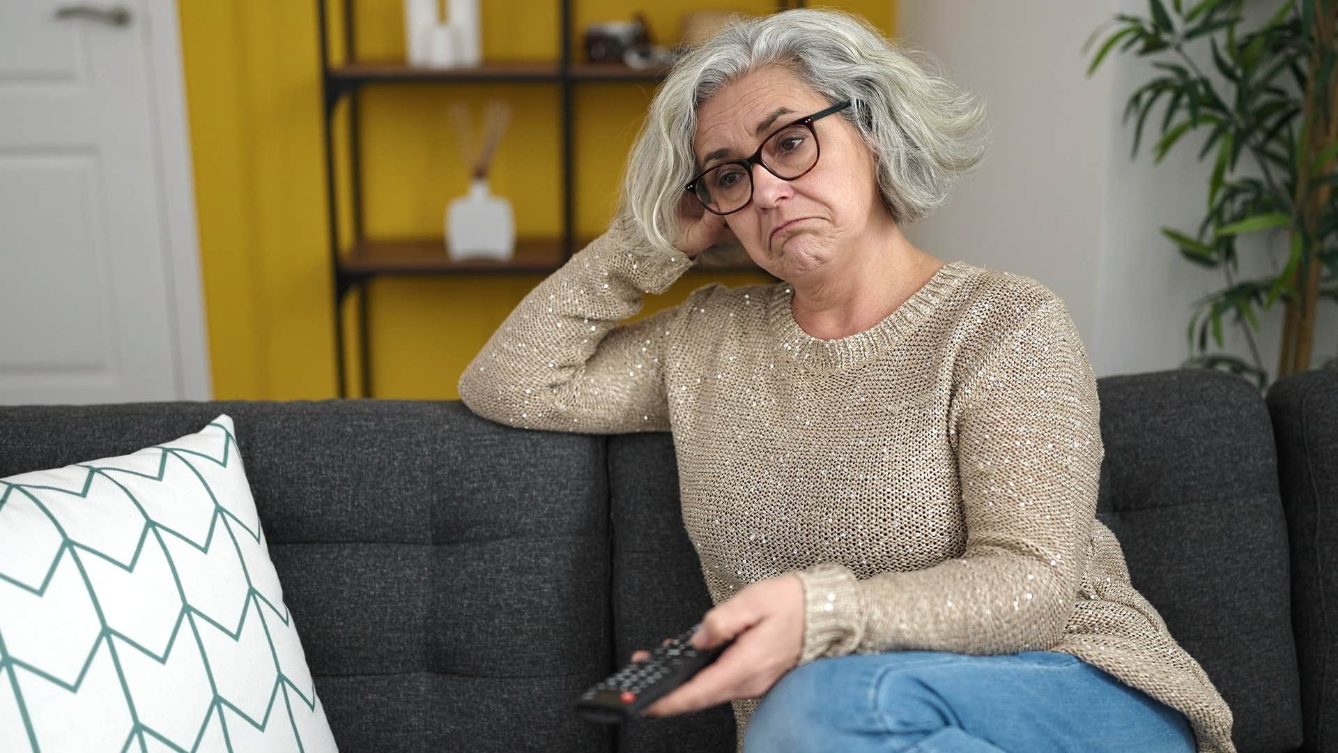older woman changing channels on tv that's always on
