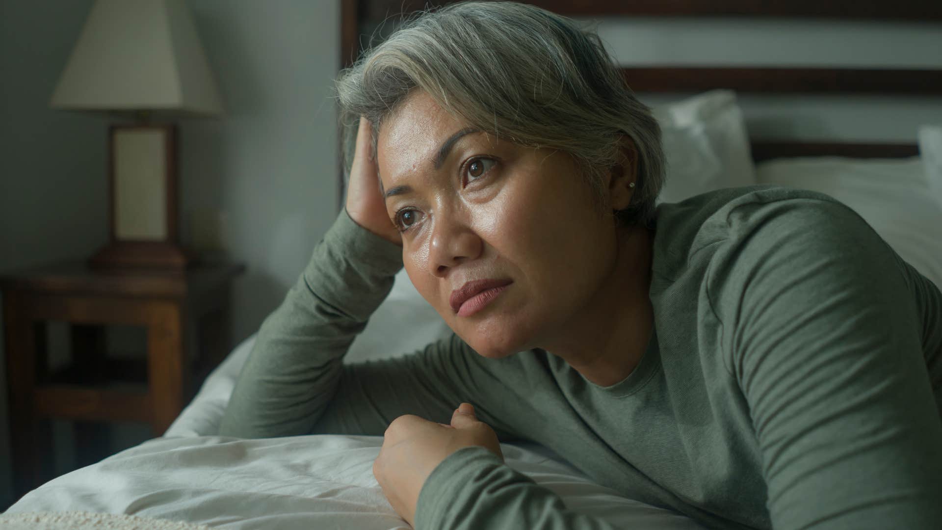 woman sitting in adult child's kid bedroom looking sad