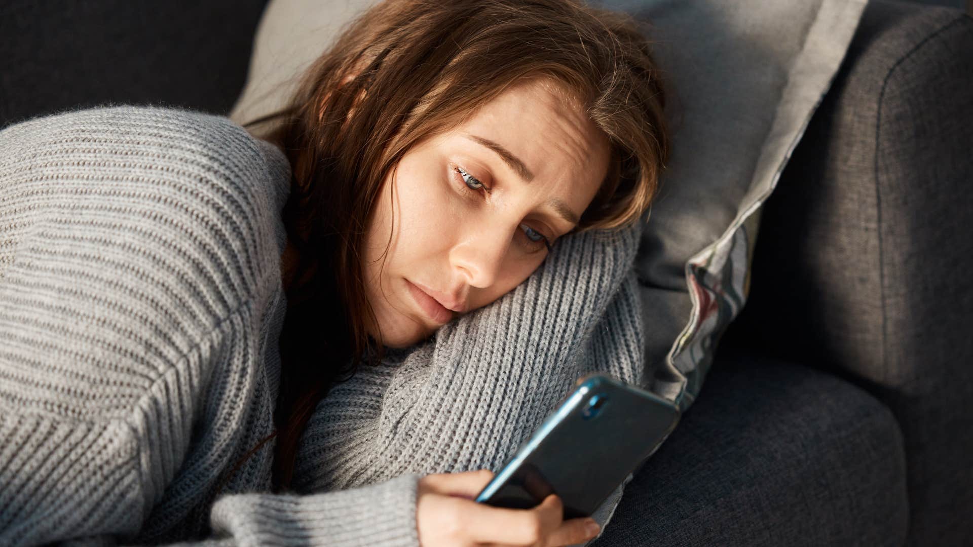 Woman who feels disconnected and lonely looking at her phone.