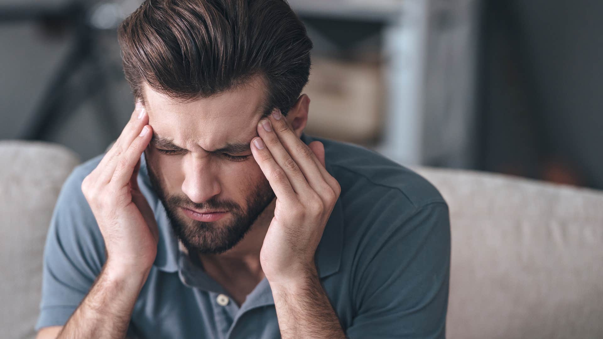 Man who feels overwhelmed by emotions sitting at home.