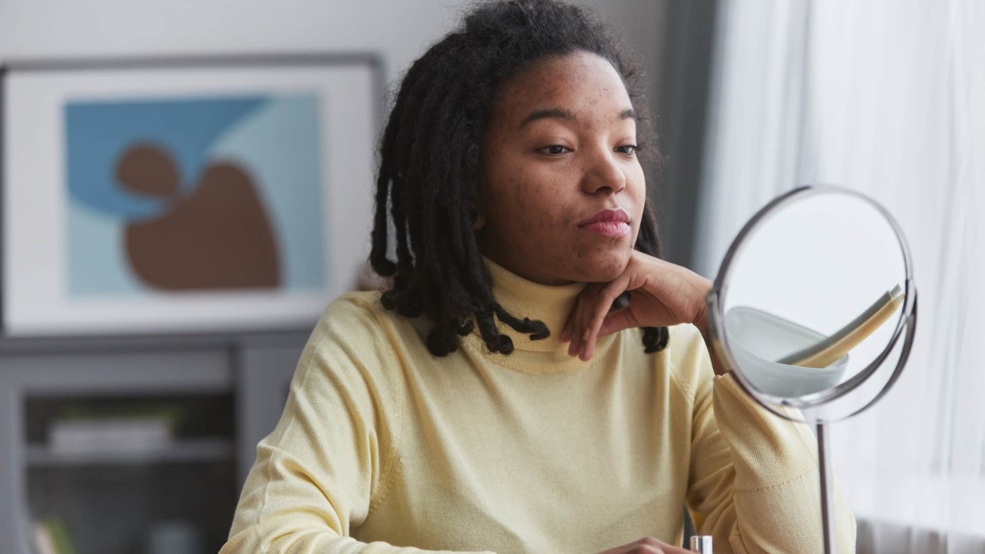 Woman who's insecure about her appearance looking in a mirror.