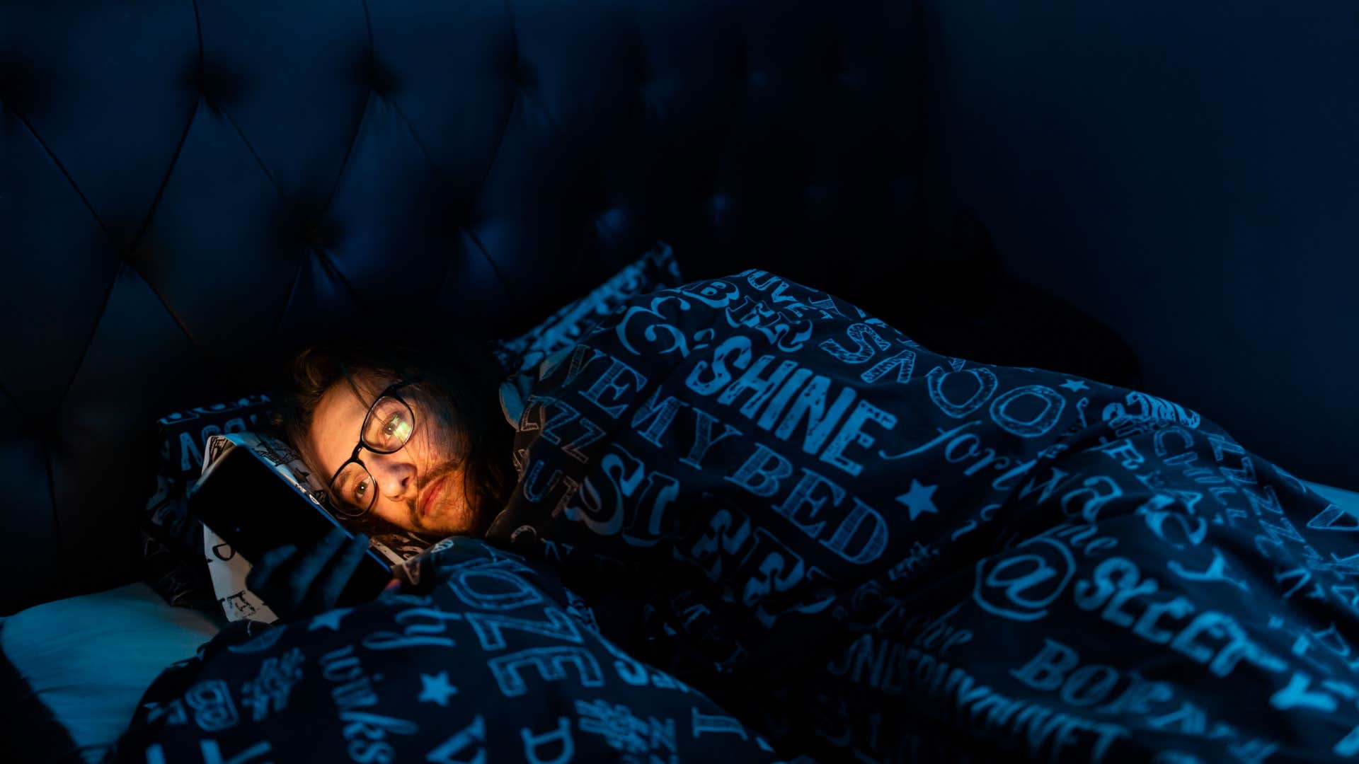 man on his phone struggling to sleep 