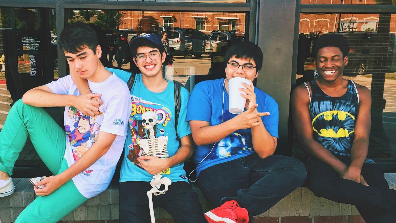 Four men sitting together on a platform, representing the wholesome trend that’s popular with Gen-Z right now