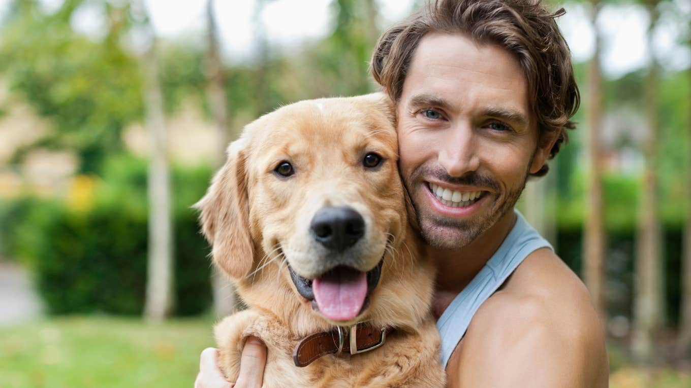 man smiling sitting next to his very happy dog