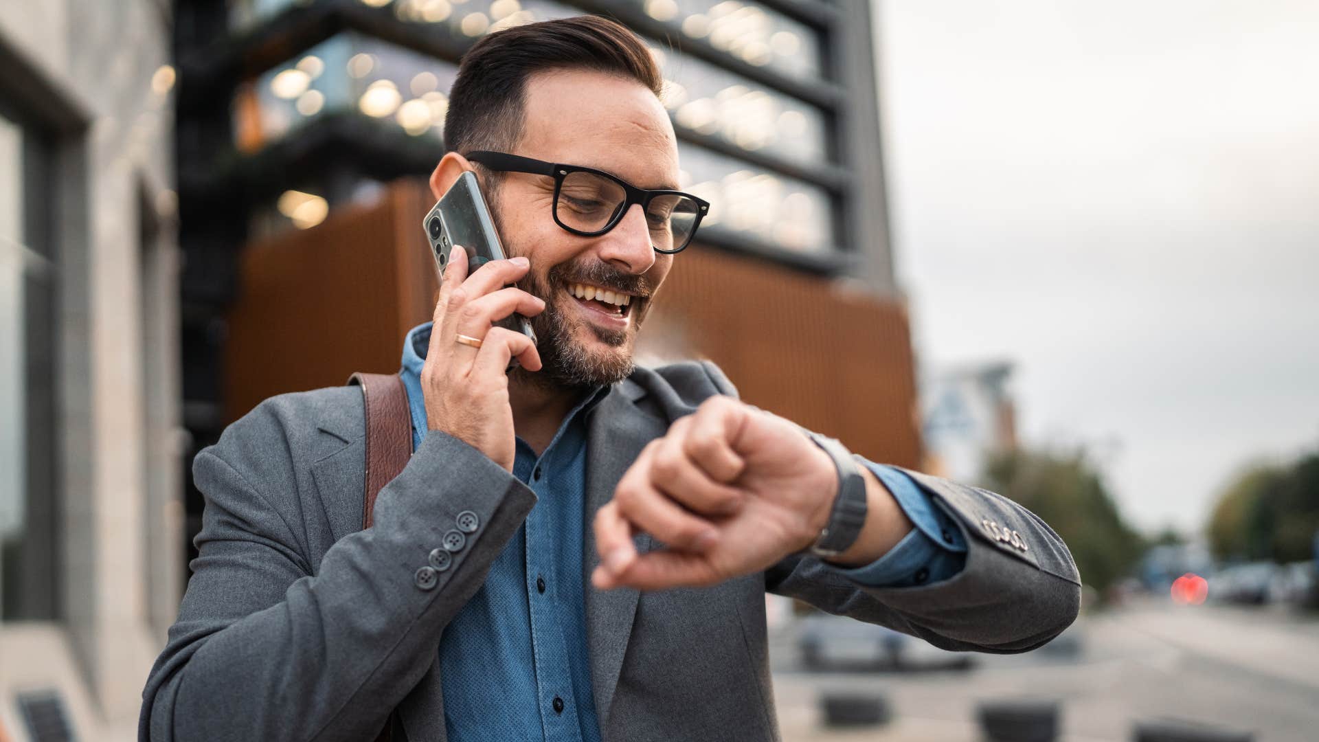 man in gray jacket checking watch as he's on the phone checking in with their mutuals 