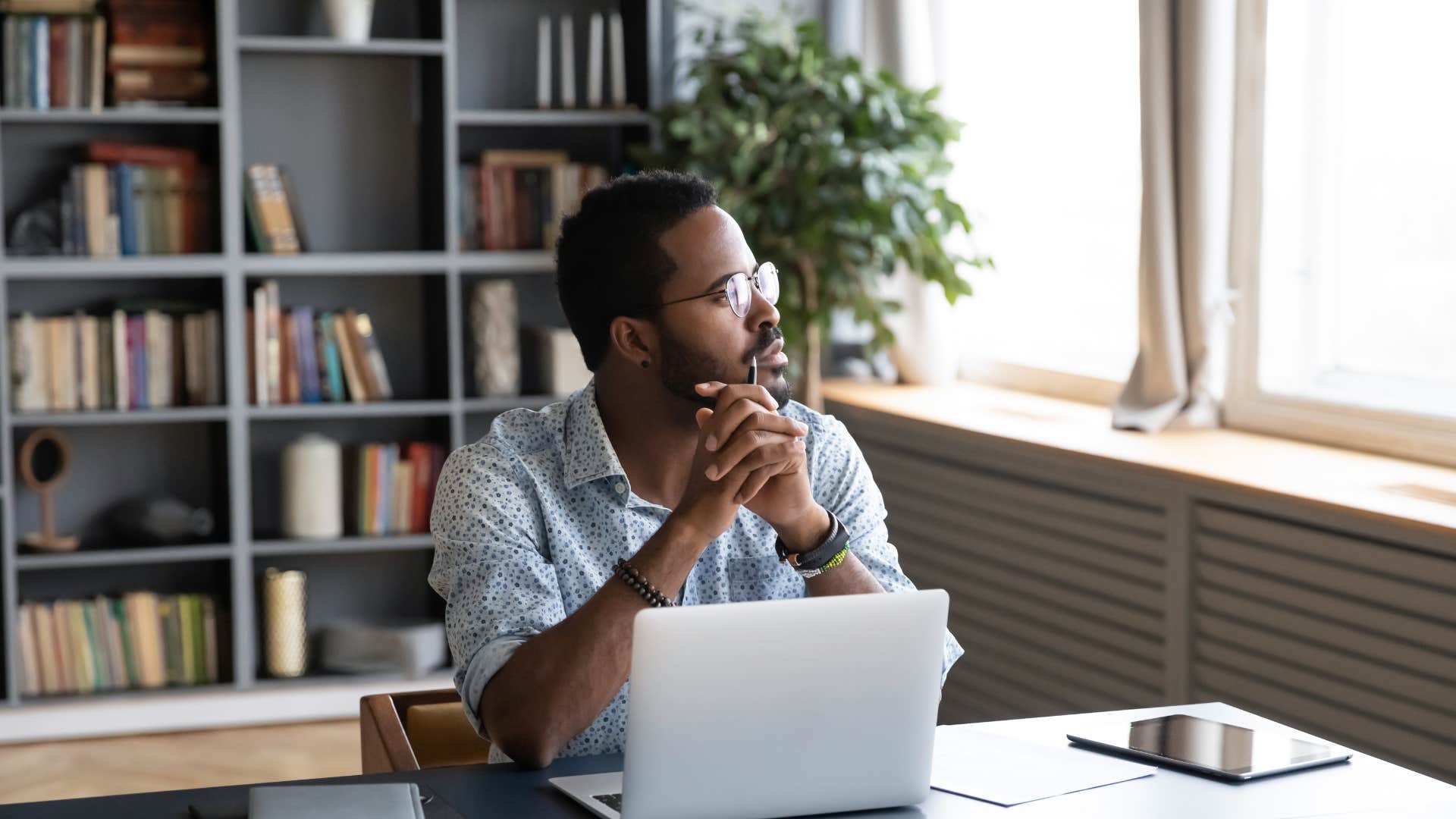 man in blue looking out of window as he plans for his future with her in mind