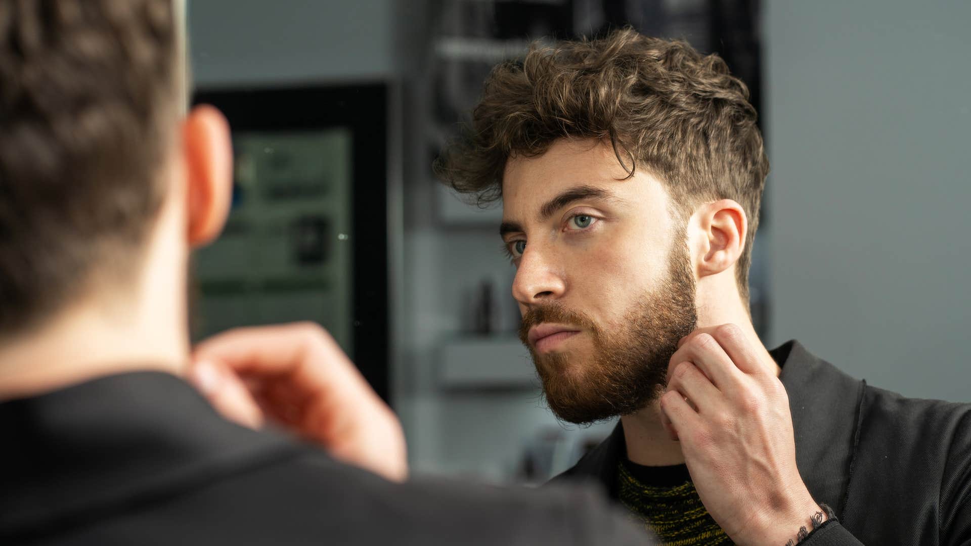 man focusing on his appearance looking in mirror