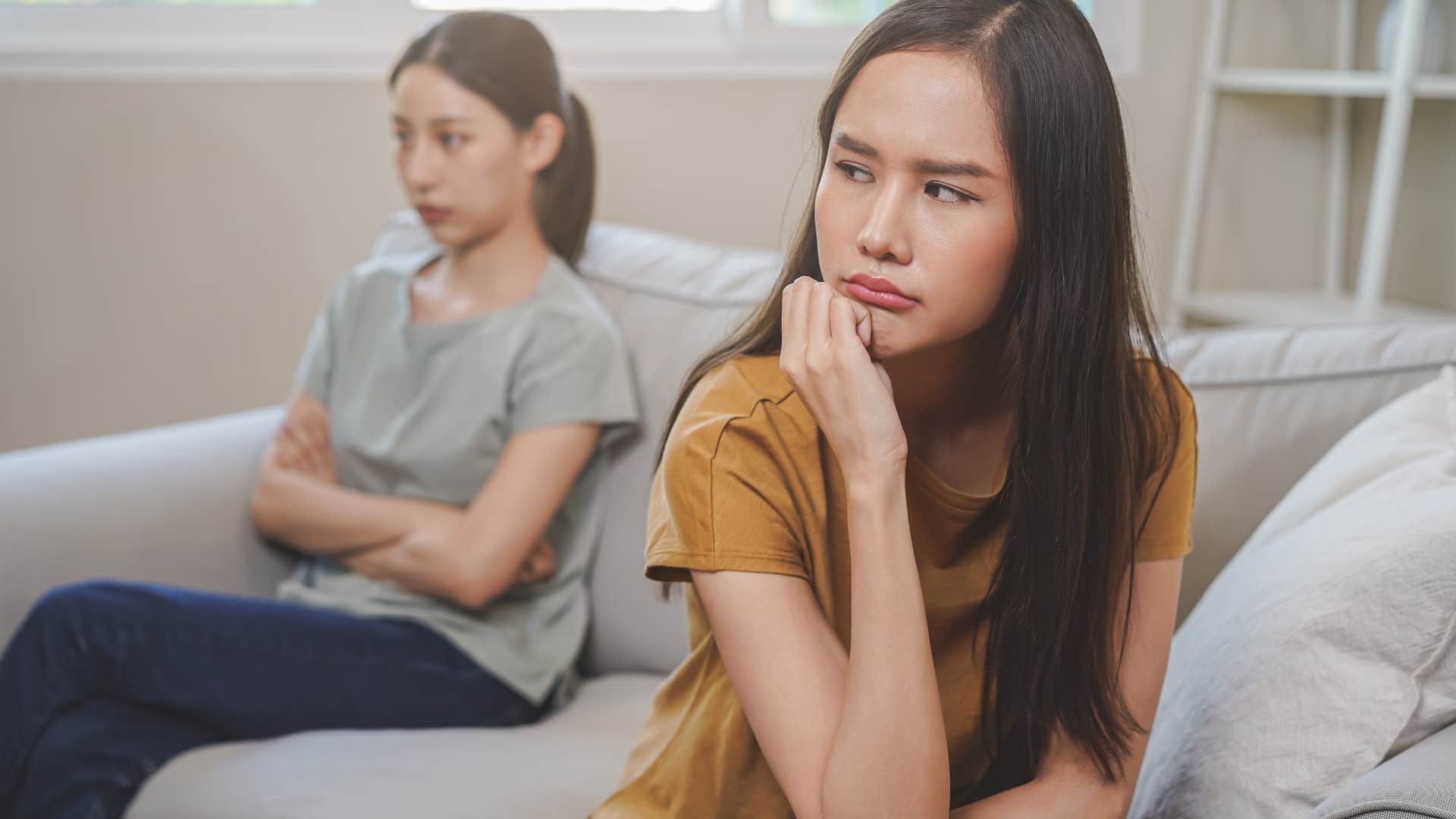 unhappy woman sitting away from friend