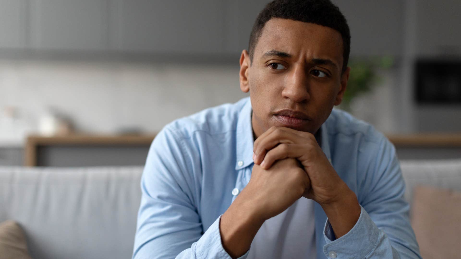 man sitting in rigid and cold home looking depressed