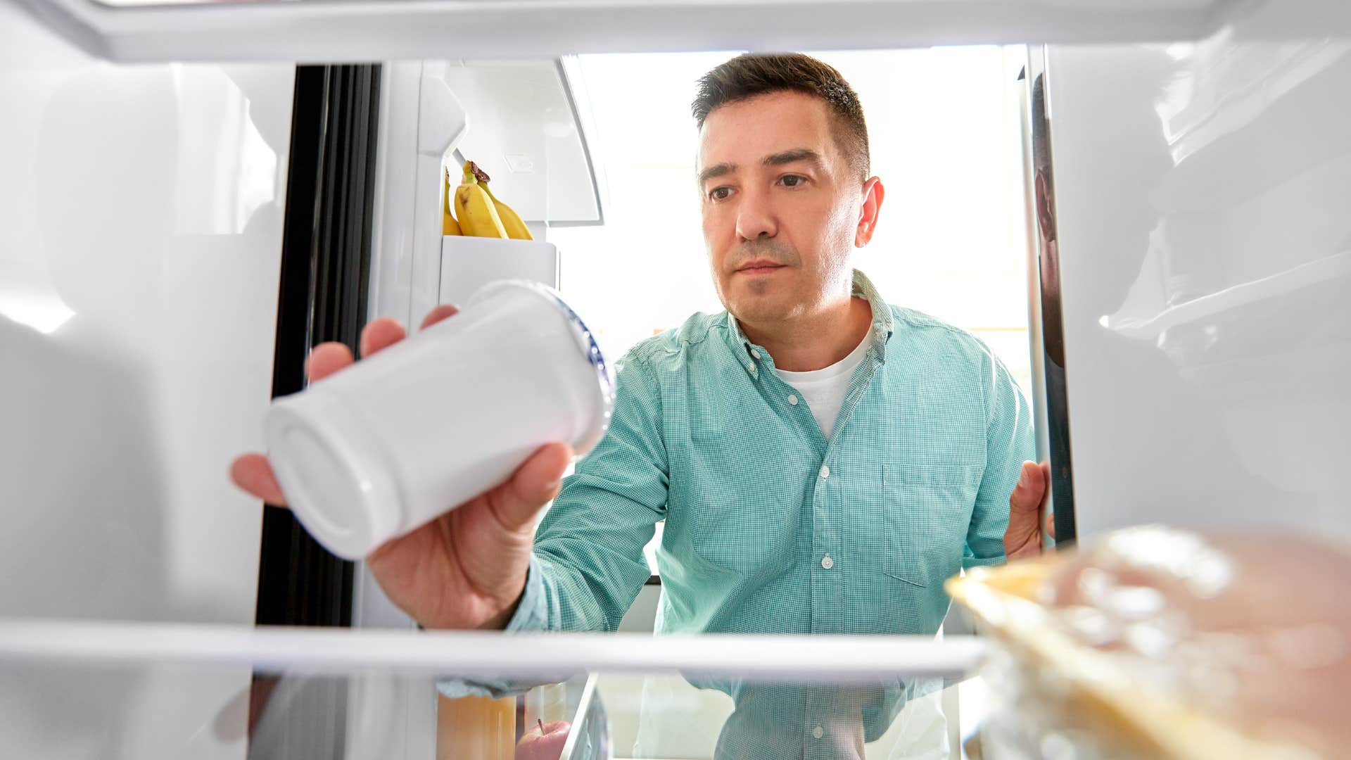 man grabbing dollar store brand food out of fridge
