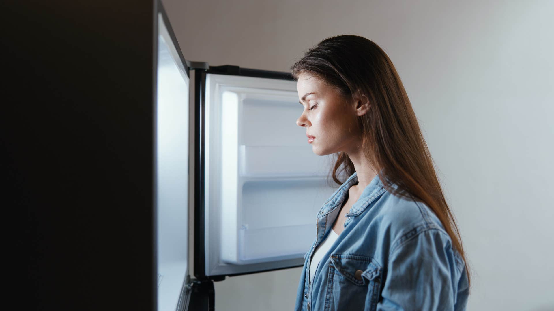 woman standing in front of the freezer looking at expired foods