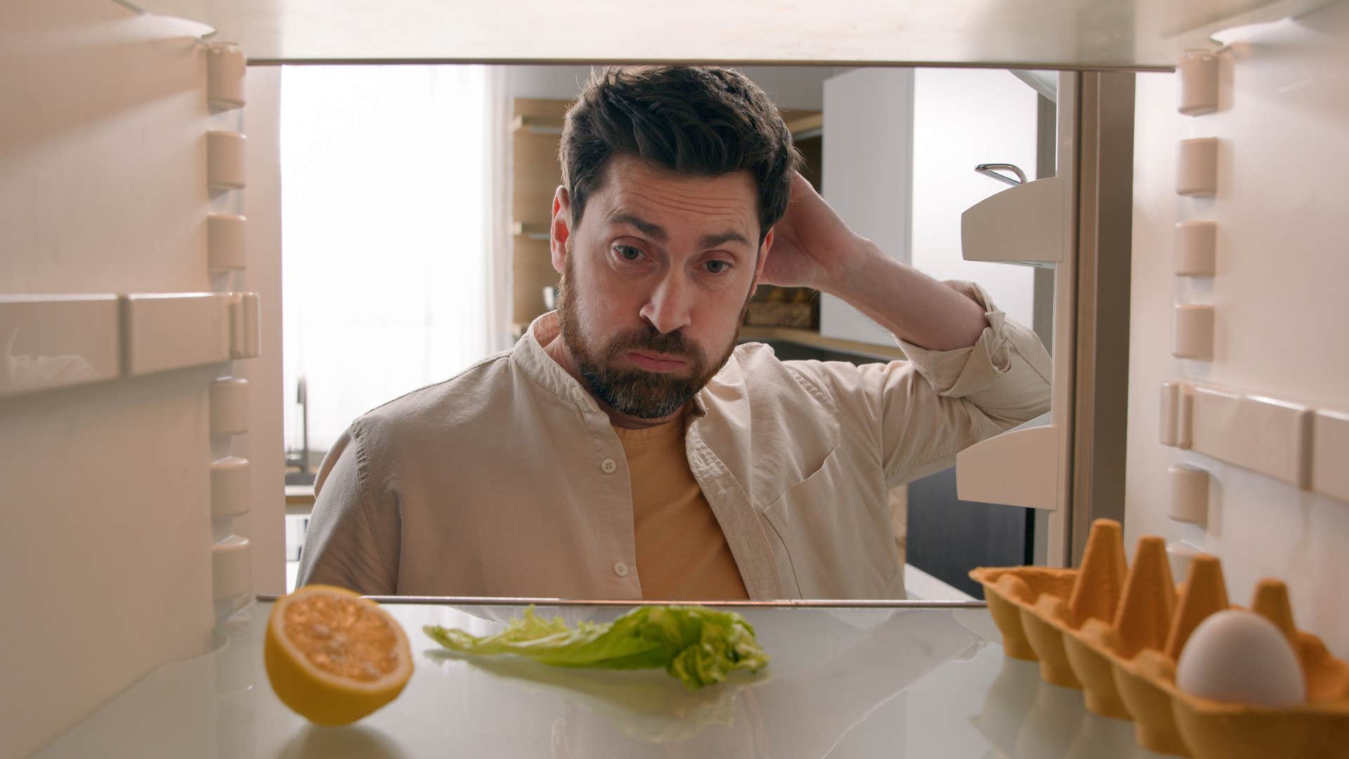man looking in fridge seeing lack of fun foods