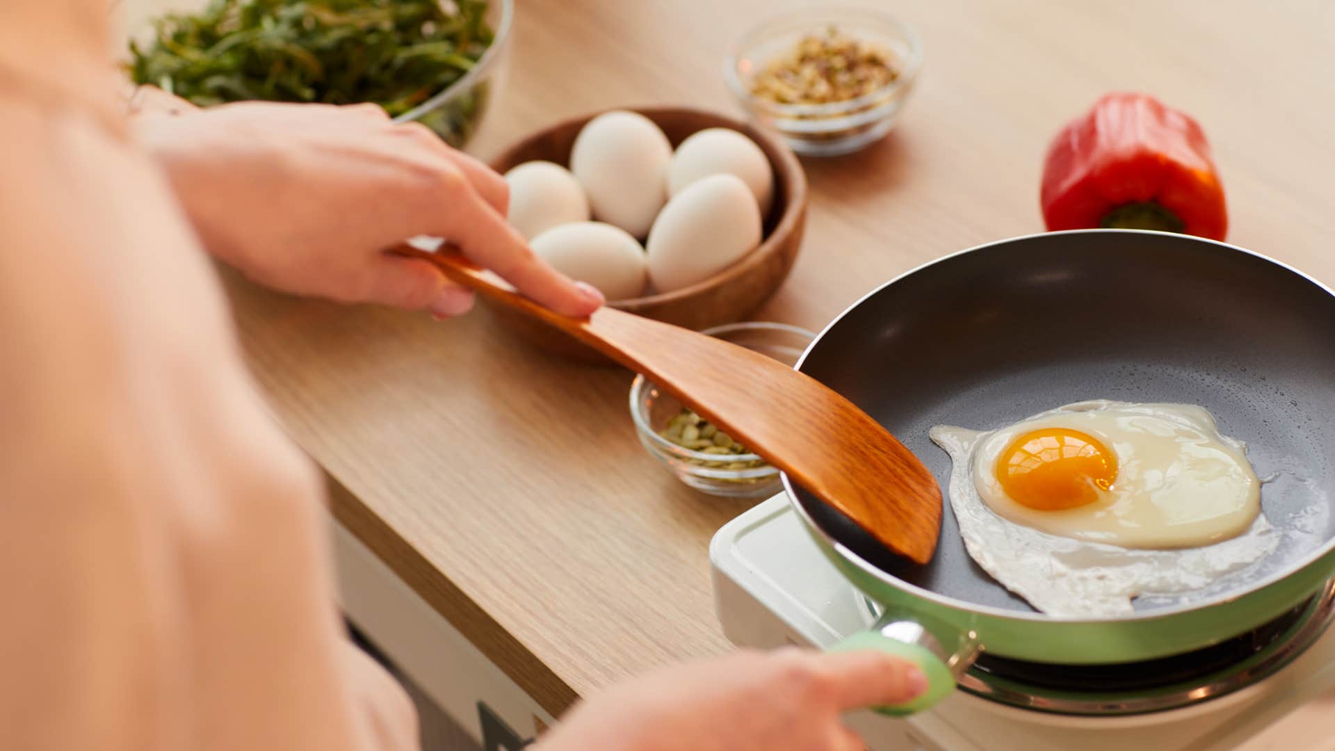 woman cooking food using single frying pan