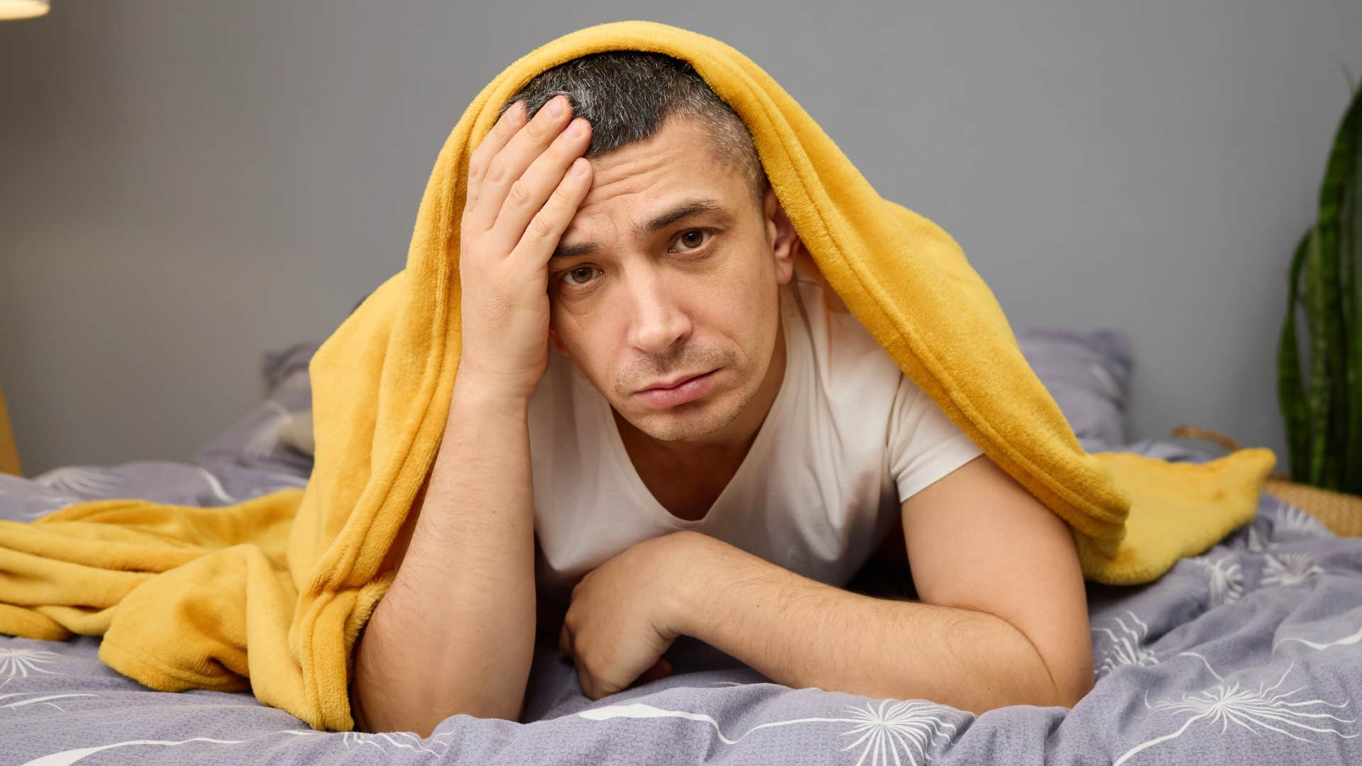 man lying in his unmade bed at home