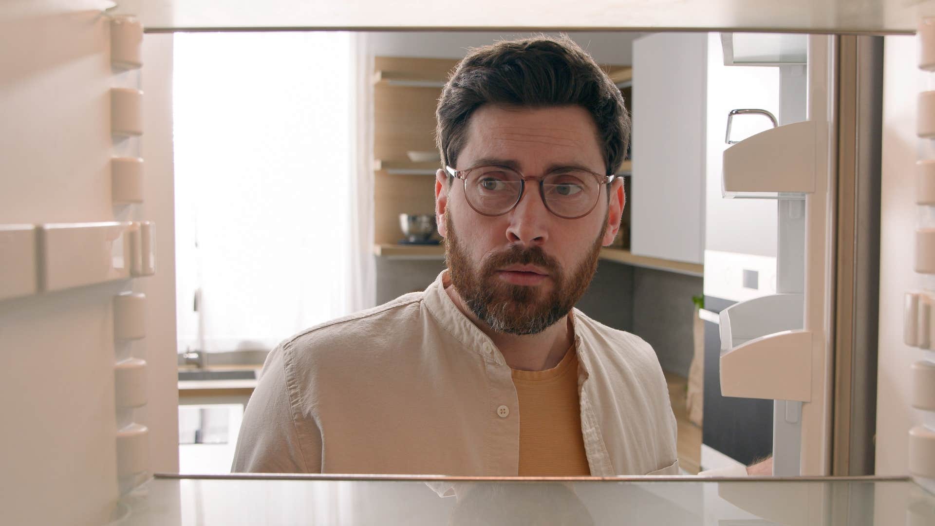 man looking in an empty fridge at home