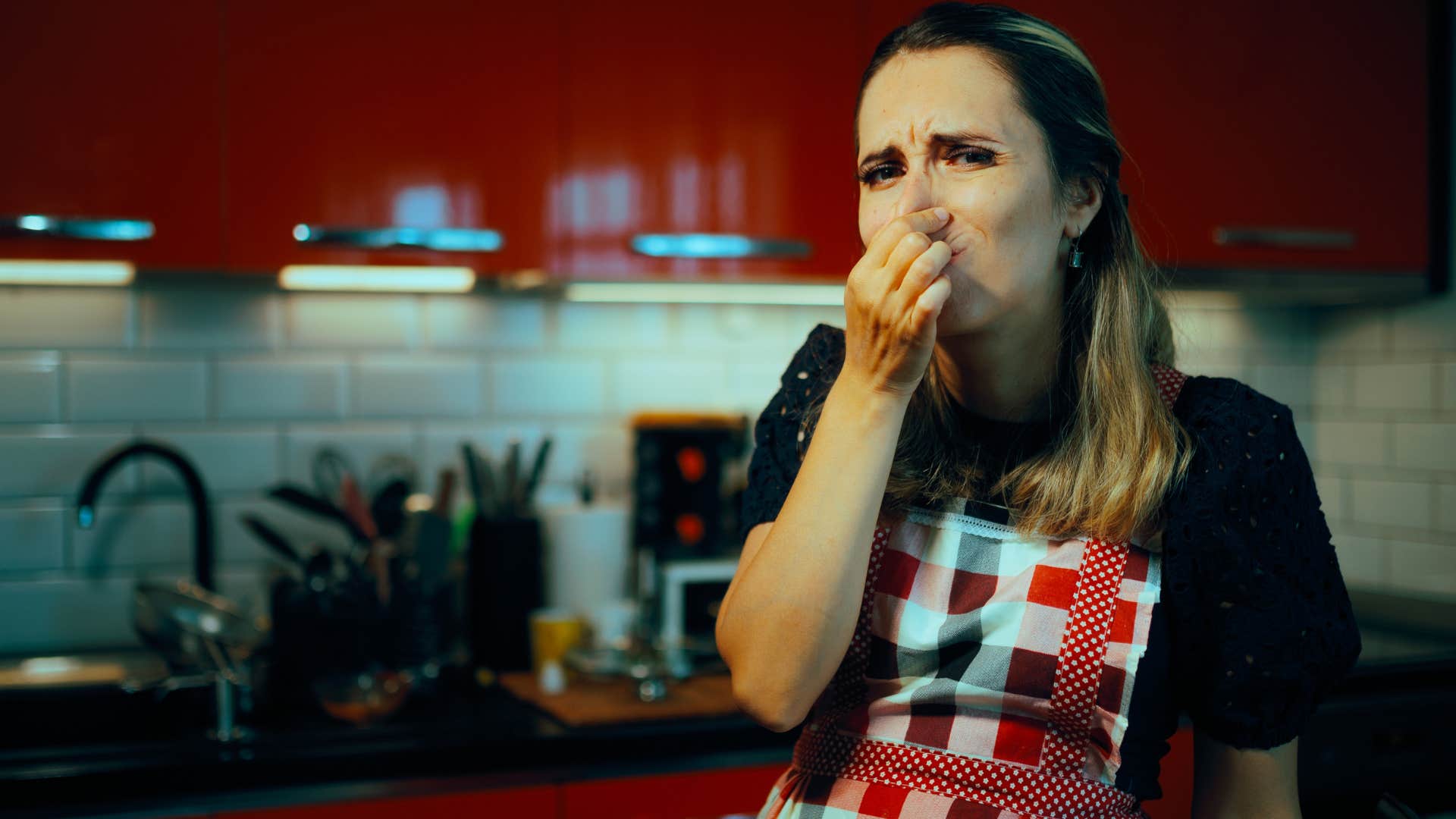 woman plugging her nose around overflowing trash bins