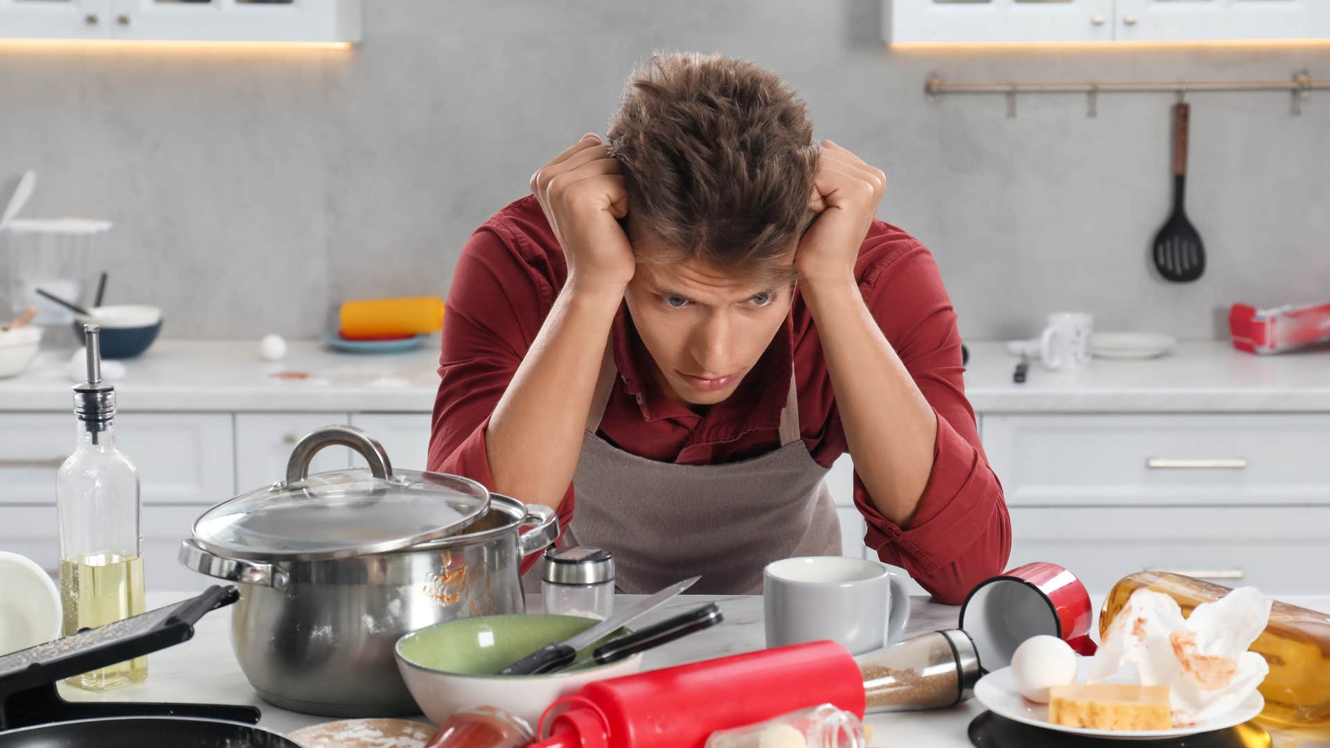 exhausted man looking at a sink full of dirty dishes