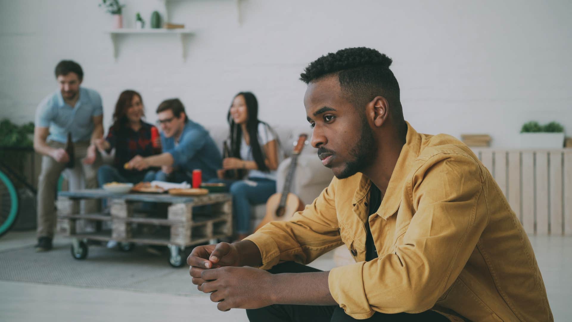 man sitting away from group of friends