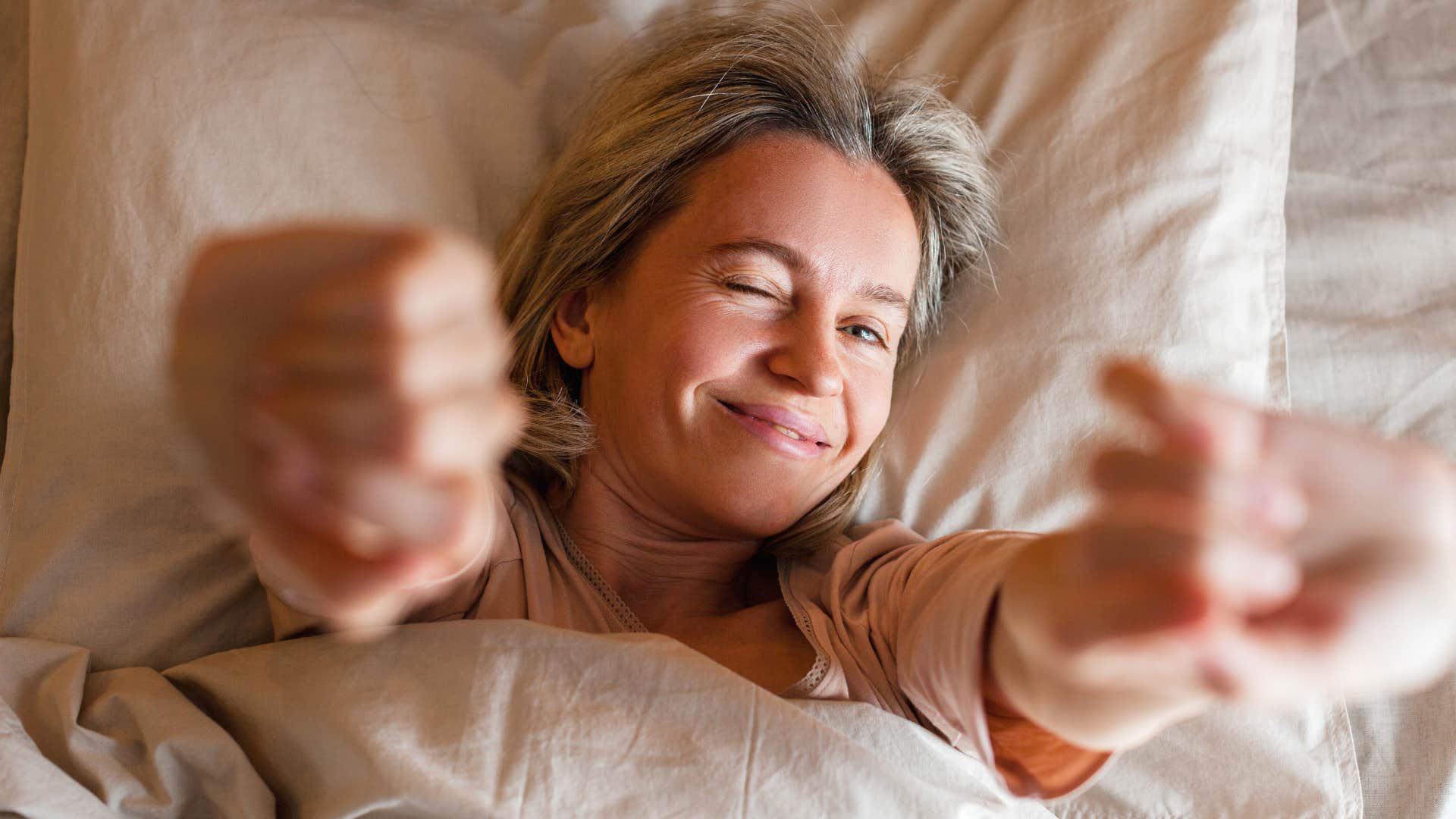 woman stretching in bed smiling