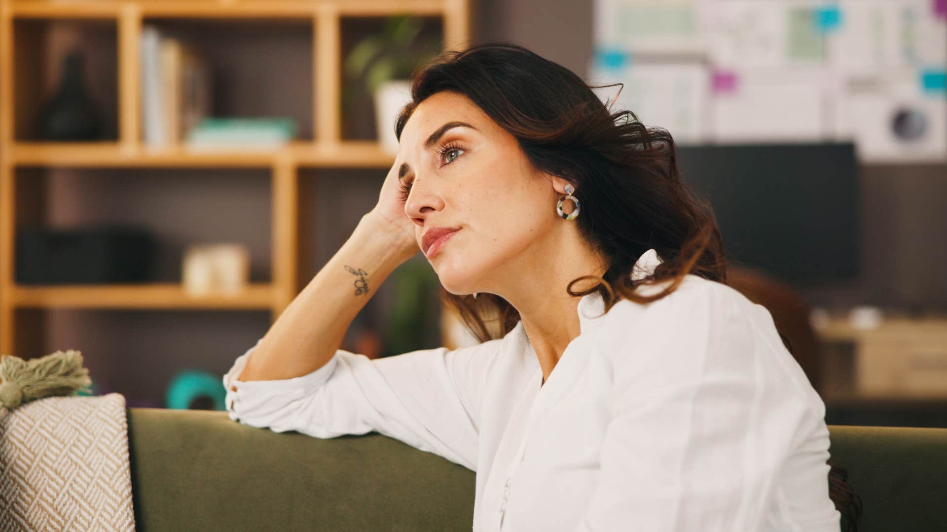 woman in white shirt sitting in silence on green couch
