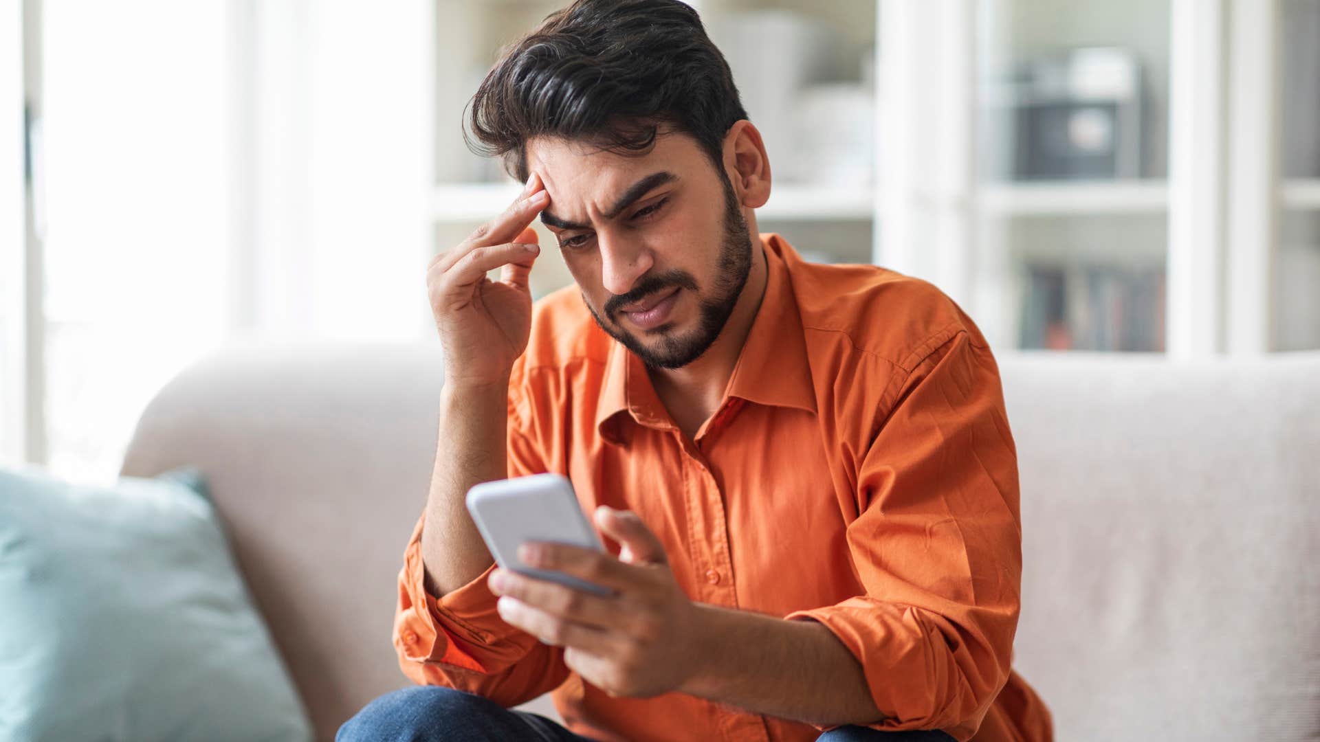 socially anxious man looking at his phone at home