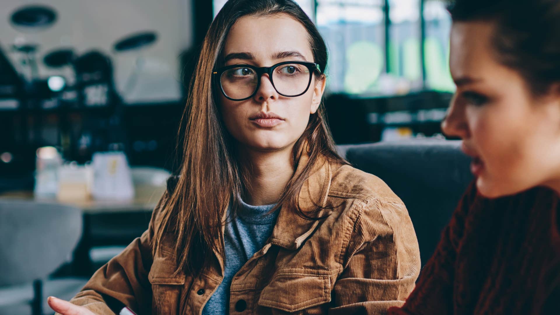 embarrassed woman over-explaining herself to a friend