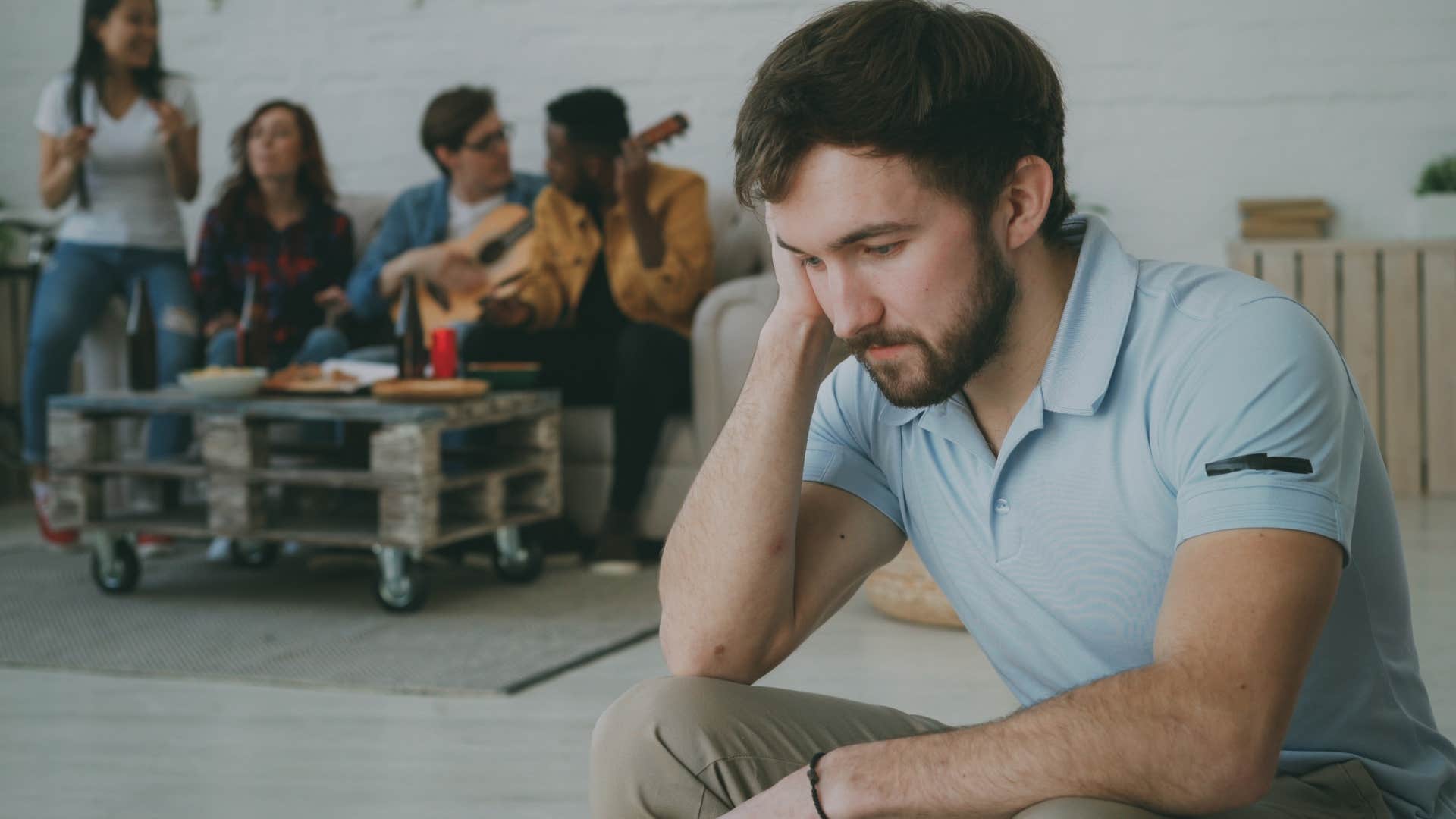 embarrassed man withdrawing from conversation with friends