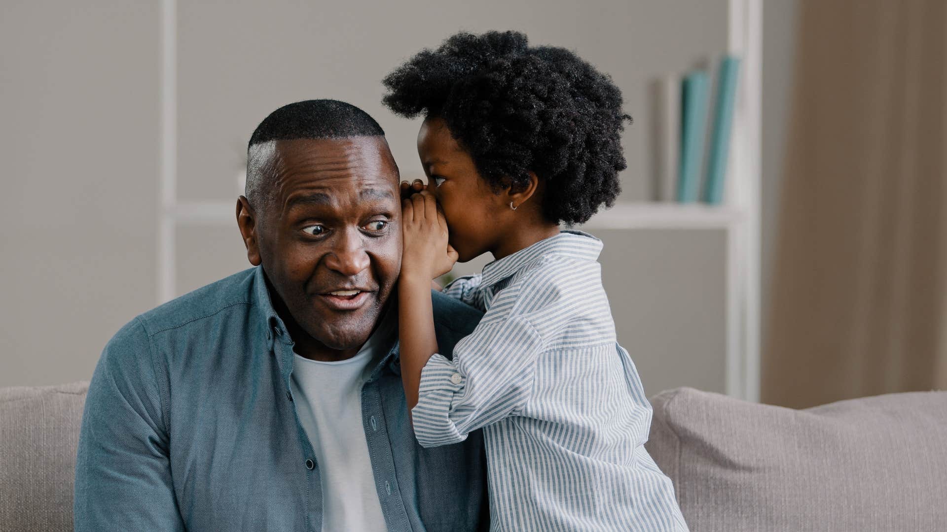 little boy whispering into dad's ear