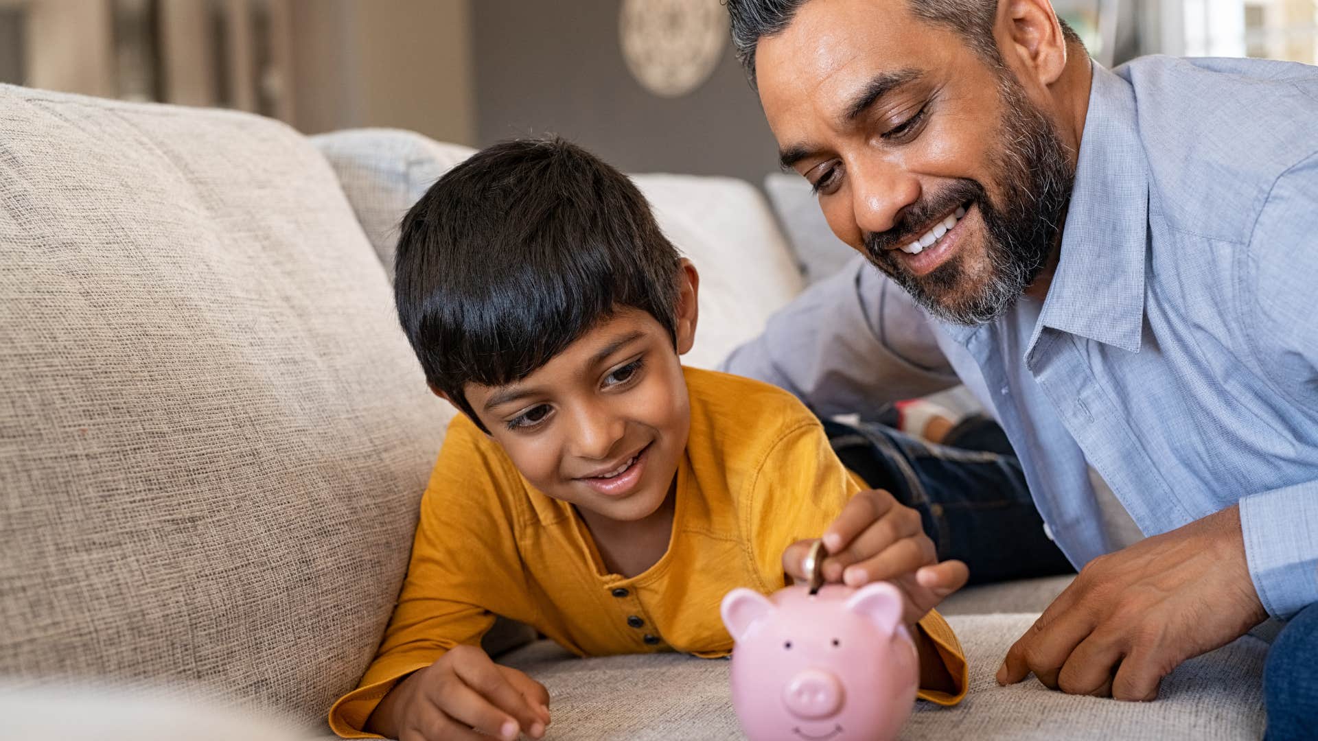 dad helping son put money into piggybank