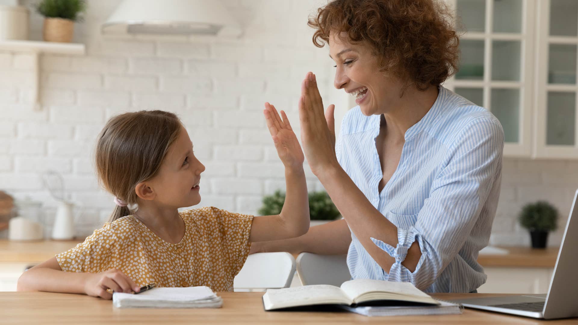 mom praising daughter while helping with schoolwork