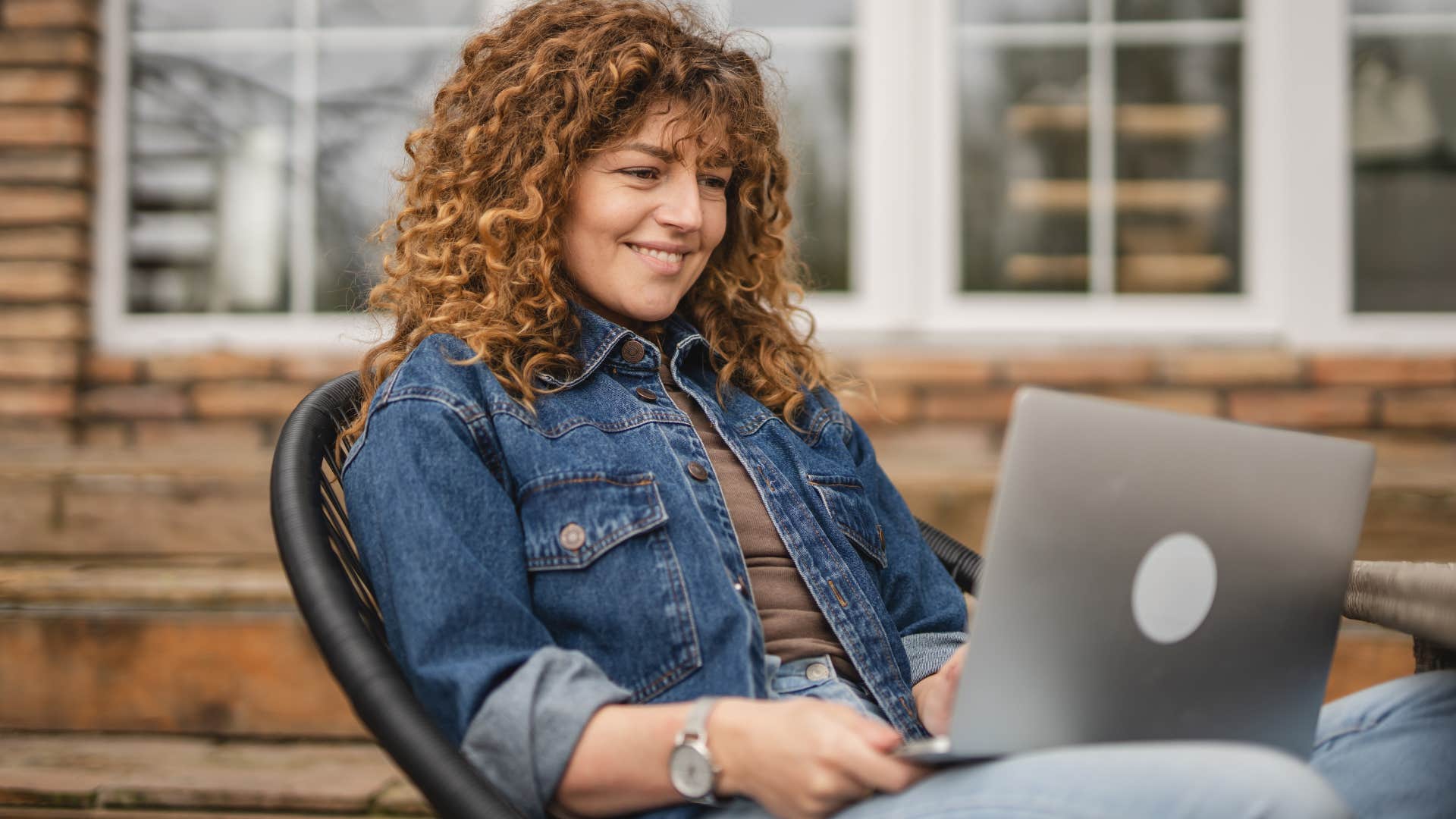 smiling woman okay with being misunderstood working on her laptop