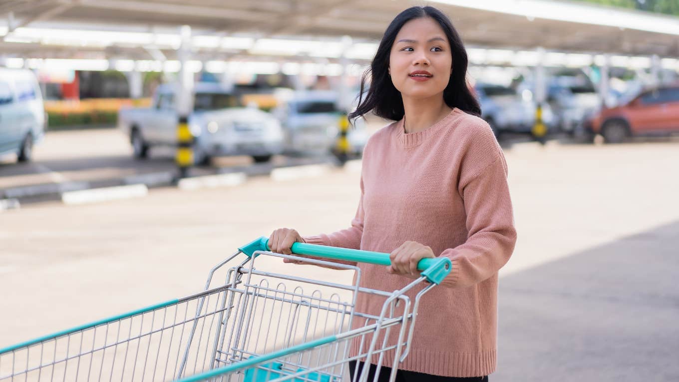woman pushing shopping cart in parking lot